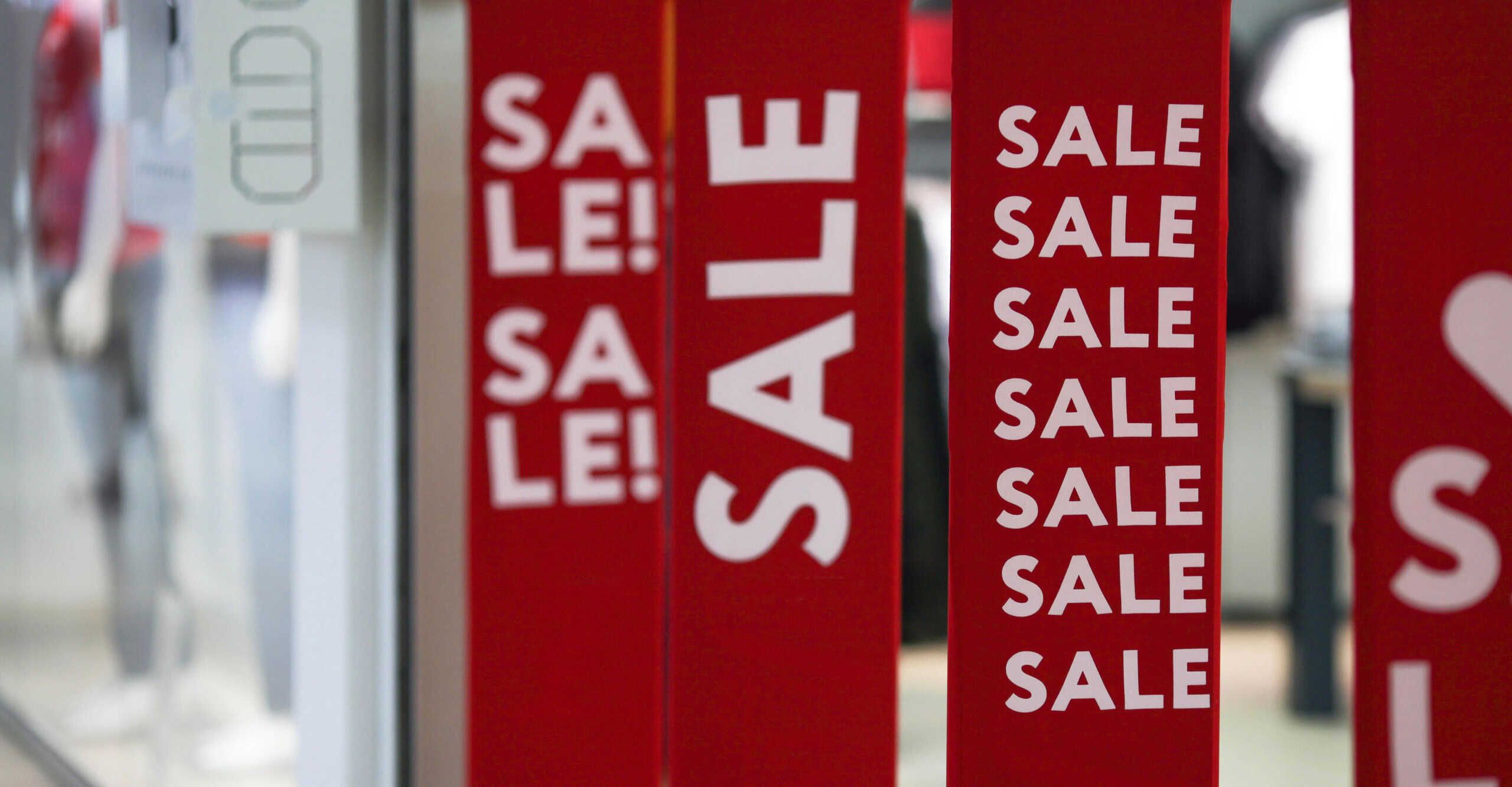 Red bright sale banner on anti-thieft gate sensor at retail shopping mall entrance. Seasonal discount offer in store. Discounts and black friday concept.