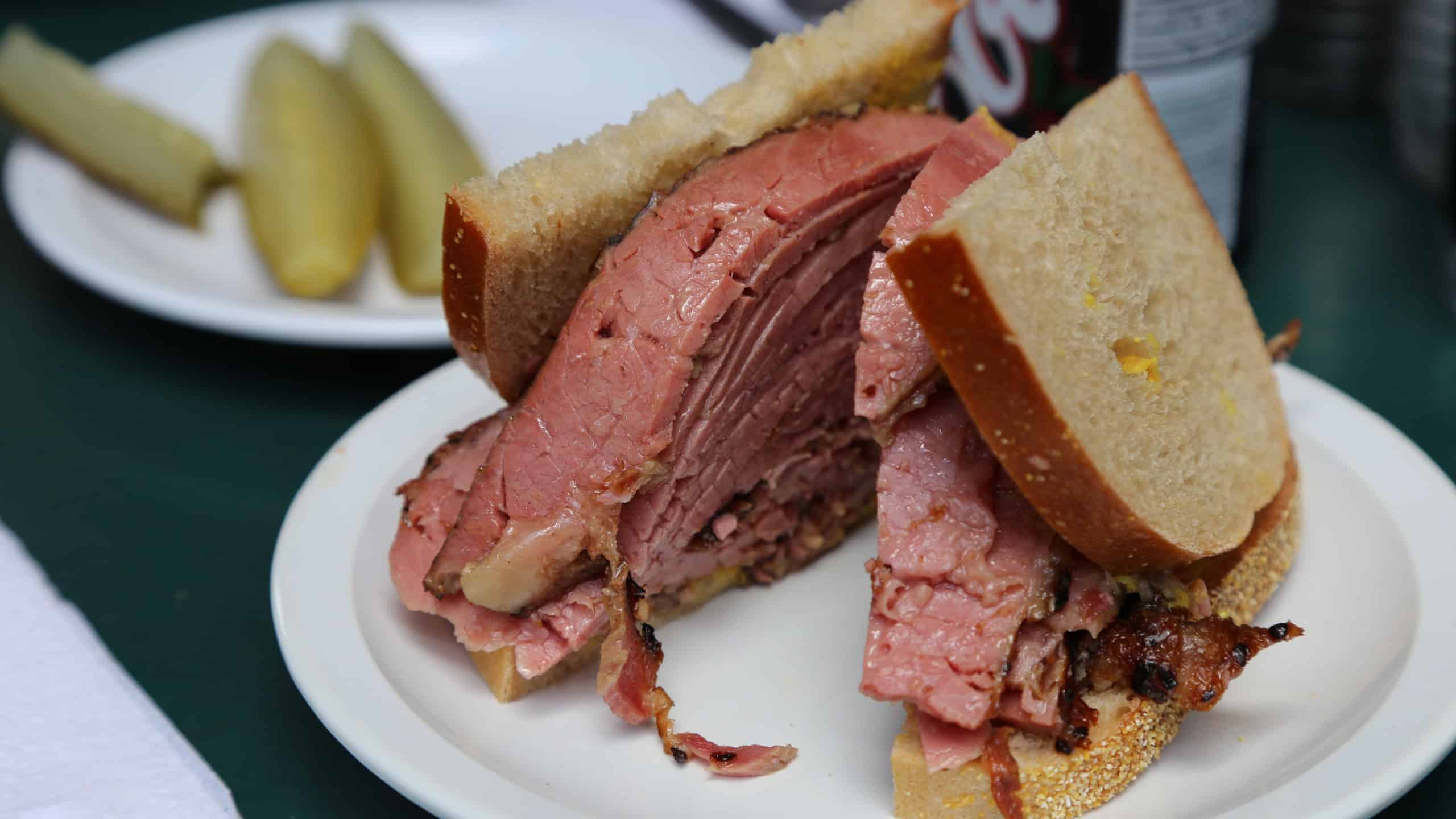 Montreal Smoked Meat Sandwich with Pickles and Soda in Background