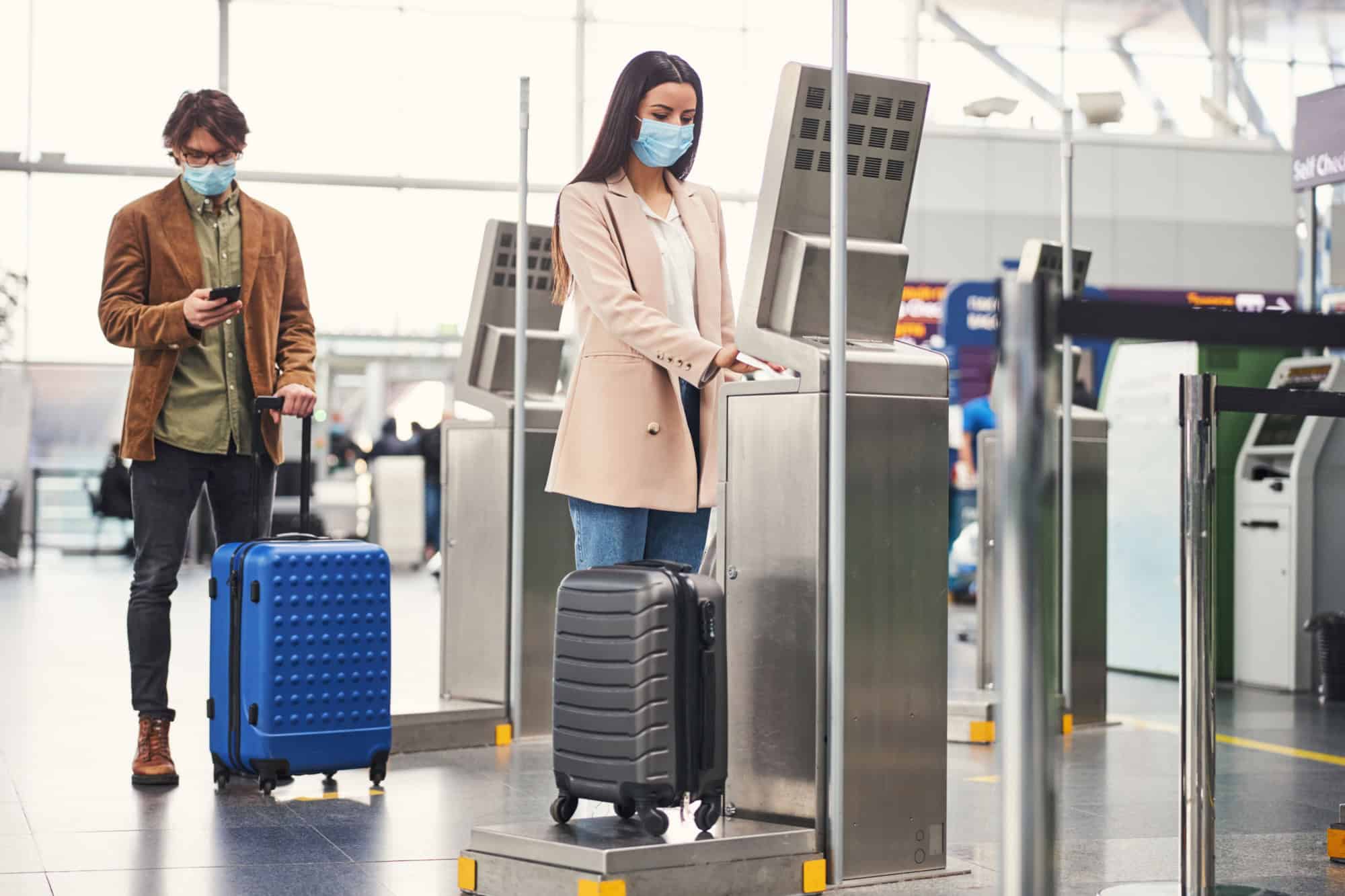 Passengers using baggage check weighing machine at airport