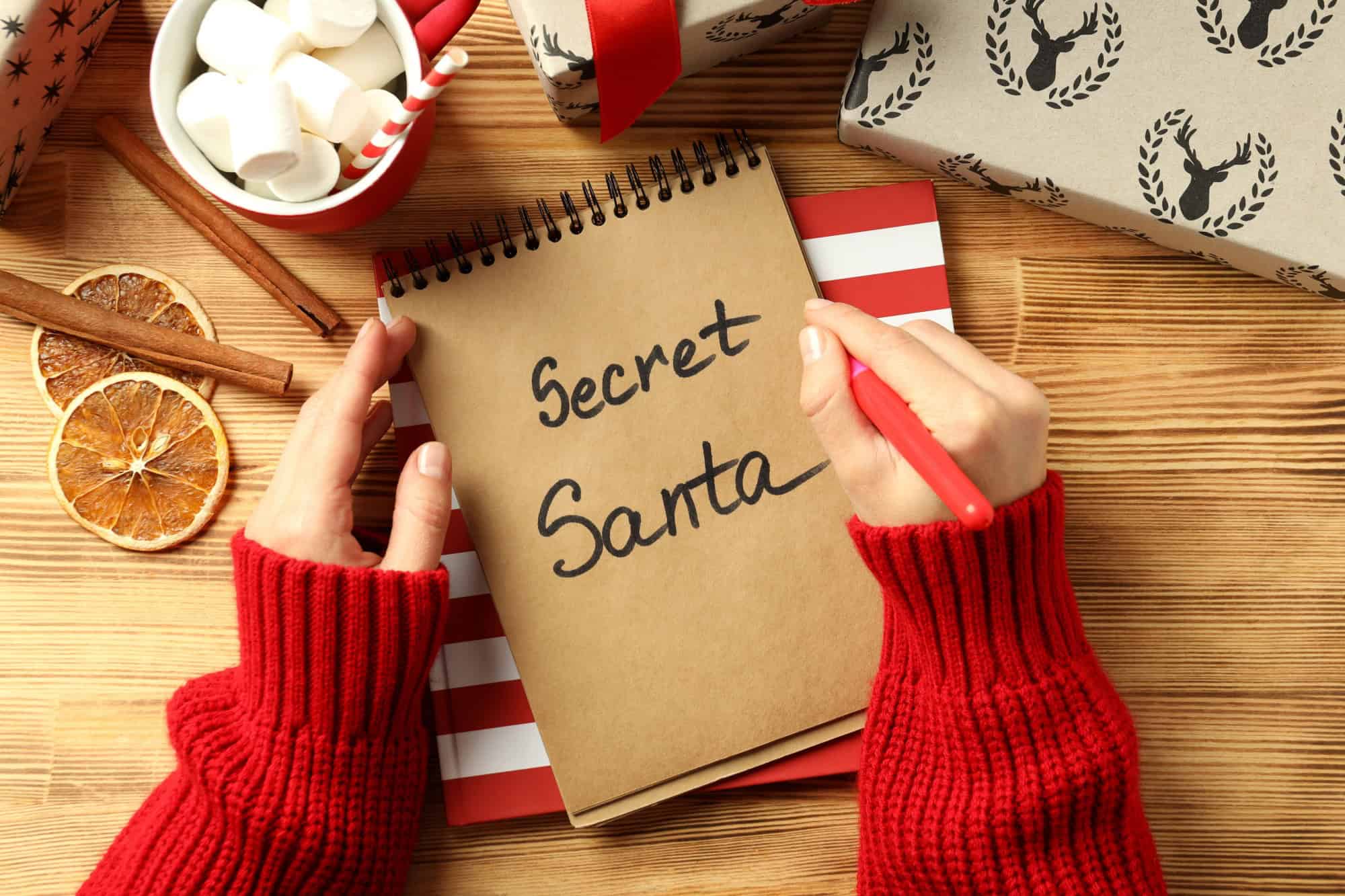 Secret Santa and Christmas composition on wooden background.