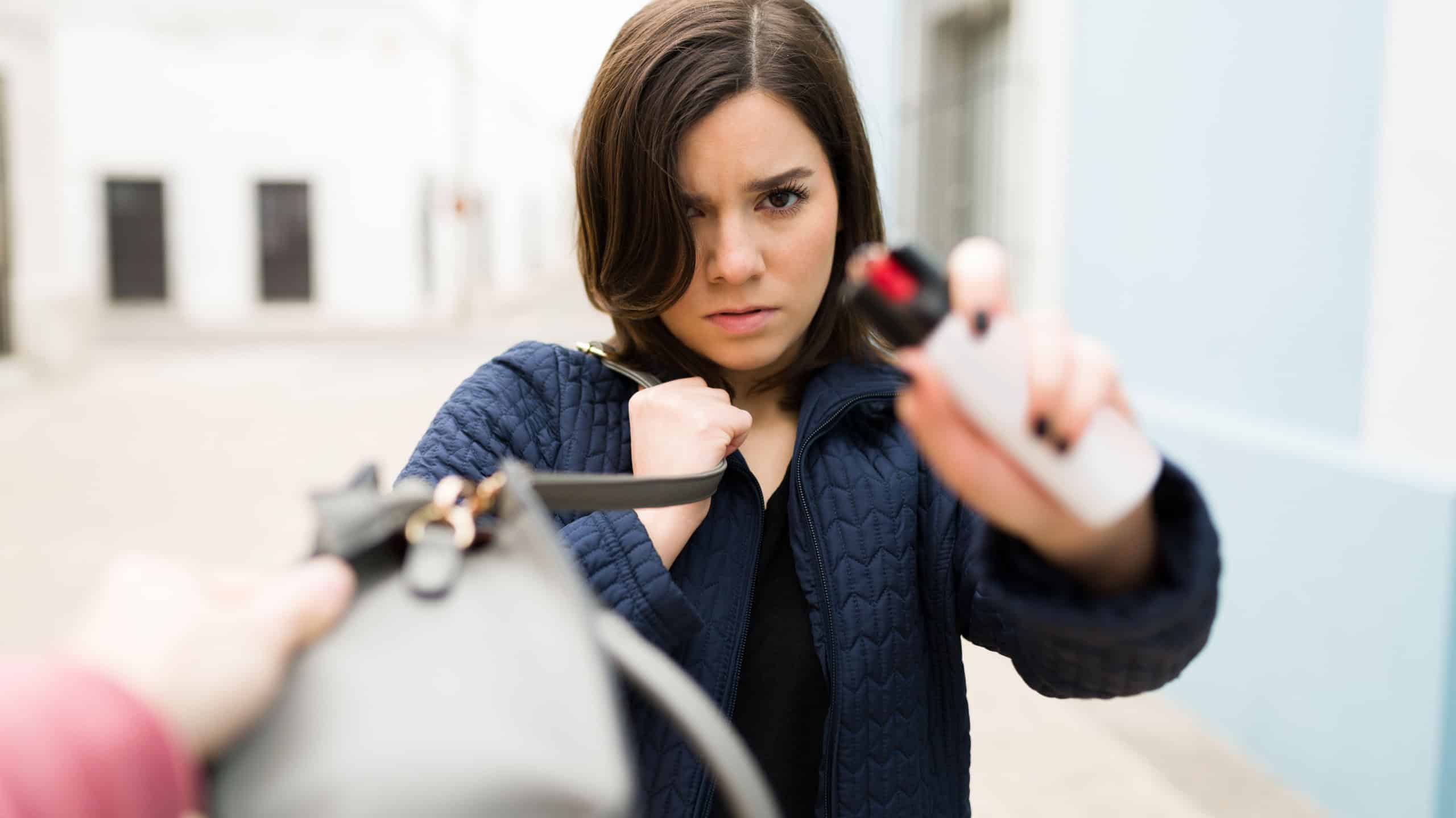 Angry caucasian woman using a pepper spray to defend herself from a robbery outdoors 