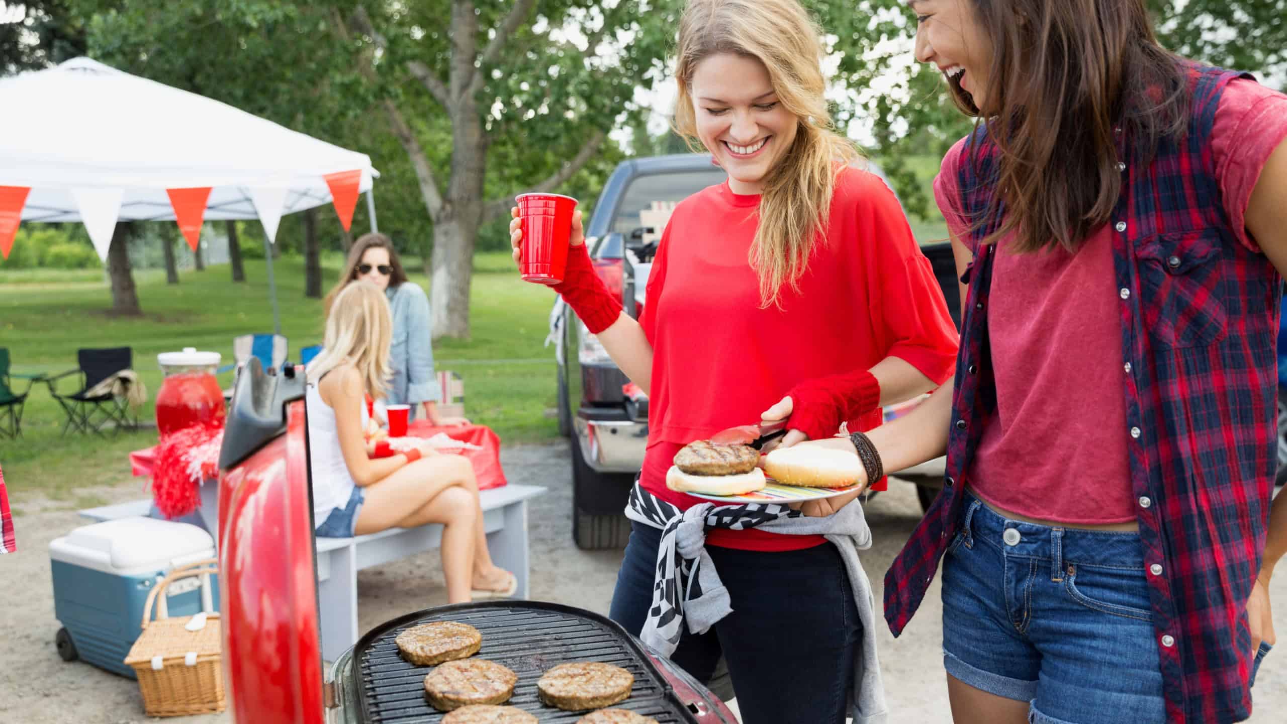 Women grilling at tailgate barbecue in field
