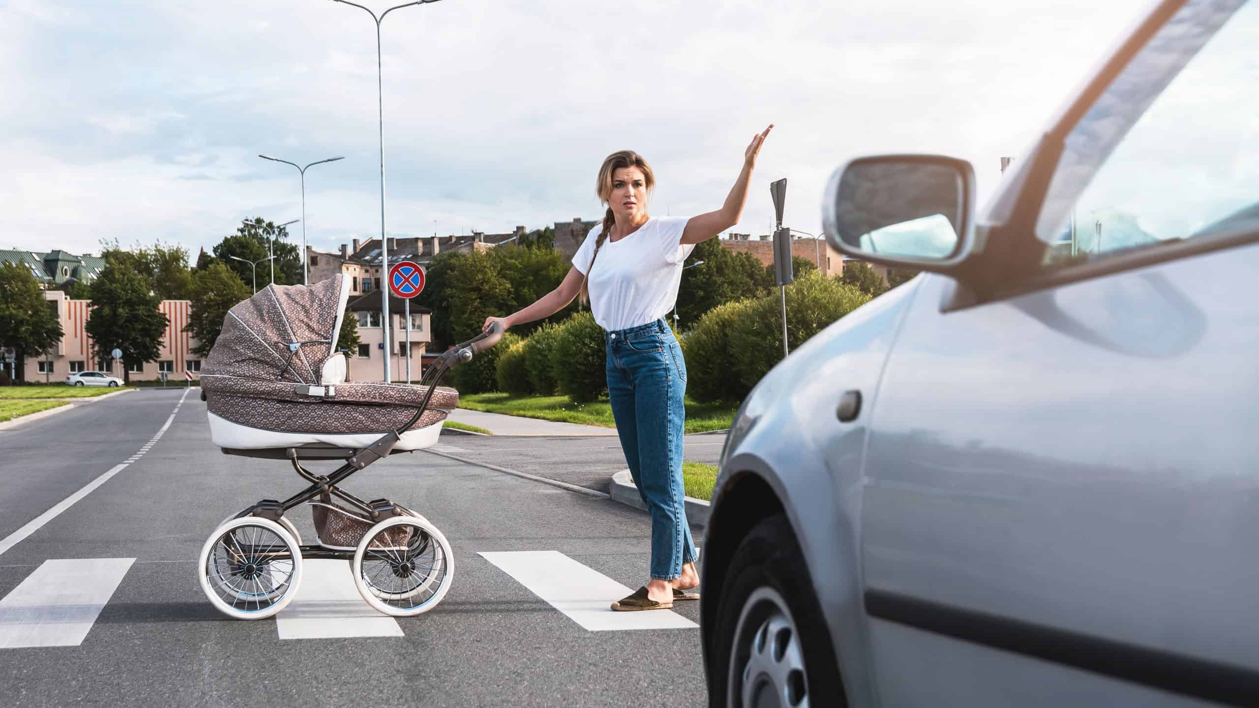Outraged mother with the baby pram conflicting with a car's driver on the crosswalk. Concepts of safety and traffic code.