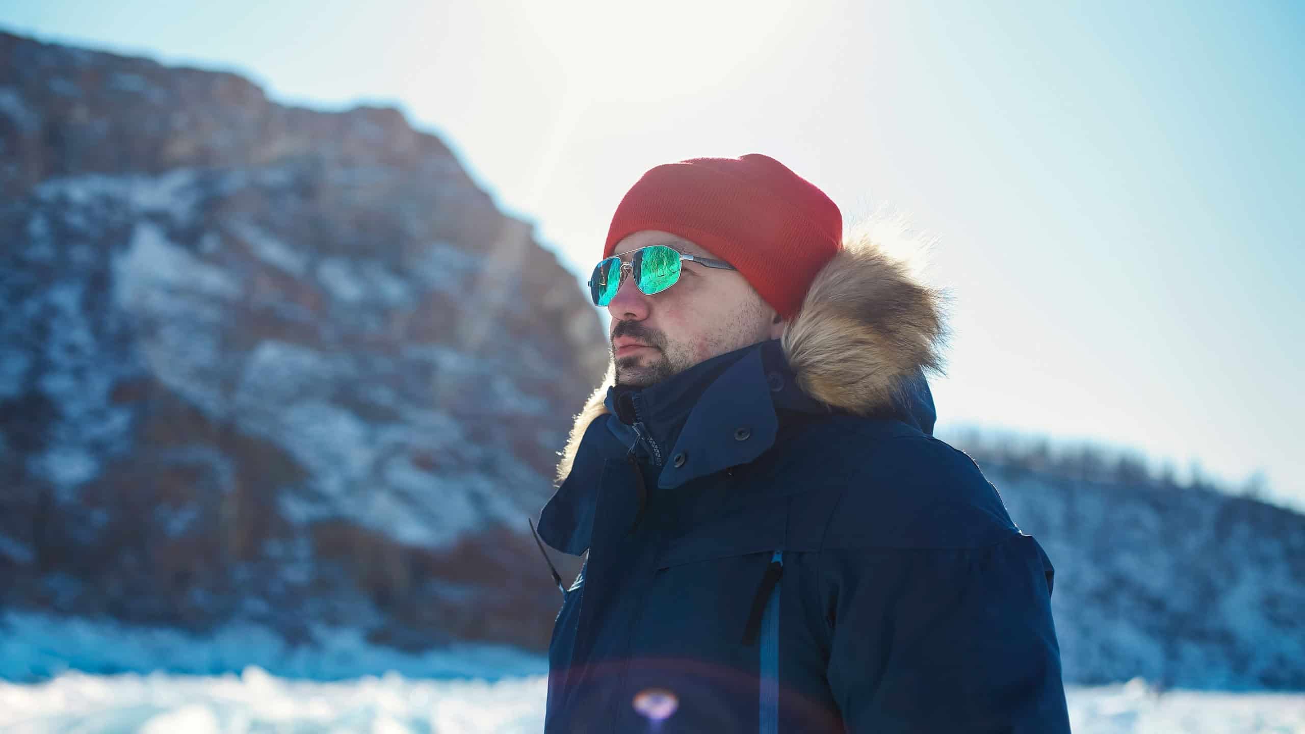 Travel and winter holiday. Lake Baikal. Portrait of the man tourist in red cap and blue jacket wearing sunglasses on ice
