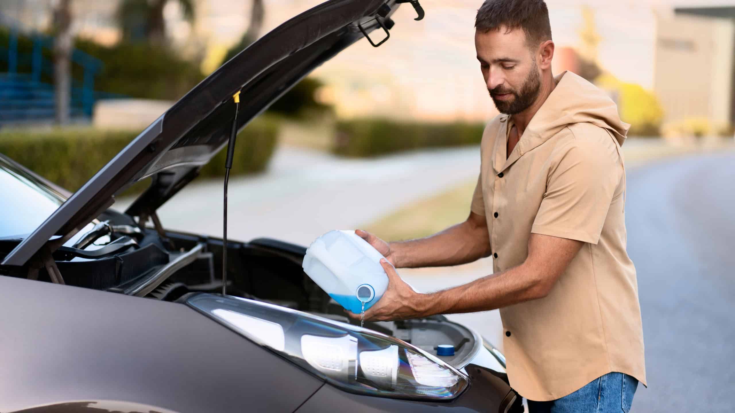 Latin man pouring windshield washer fluid for clearing car. Car service concept