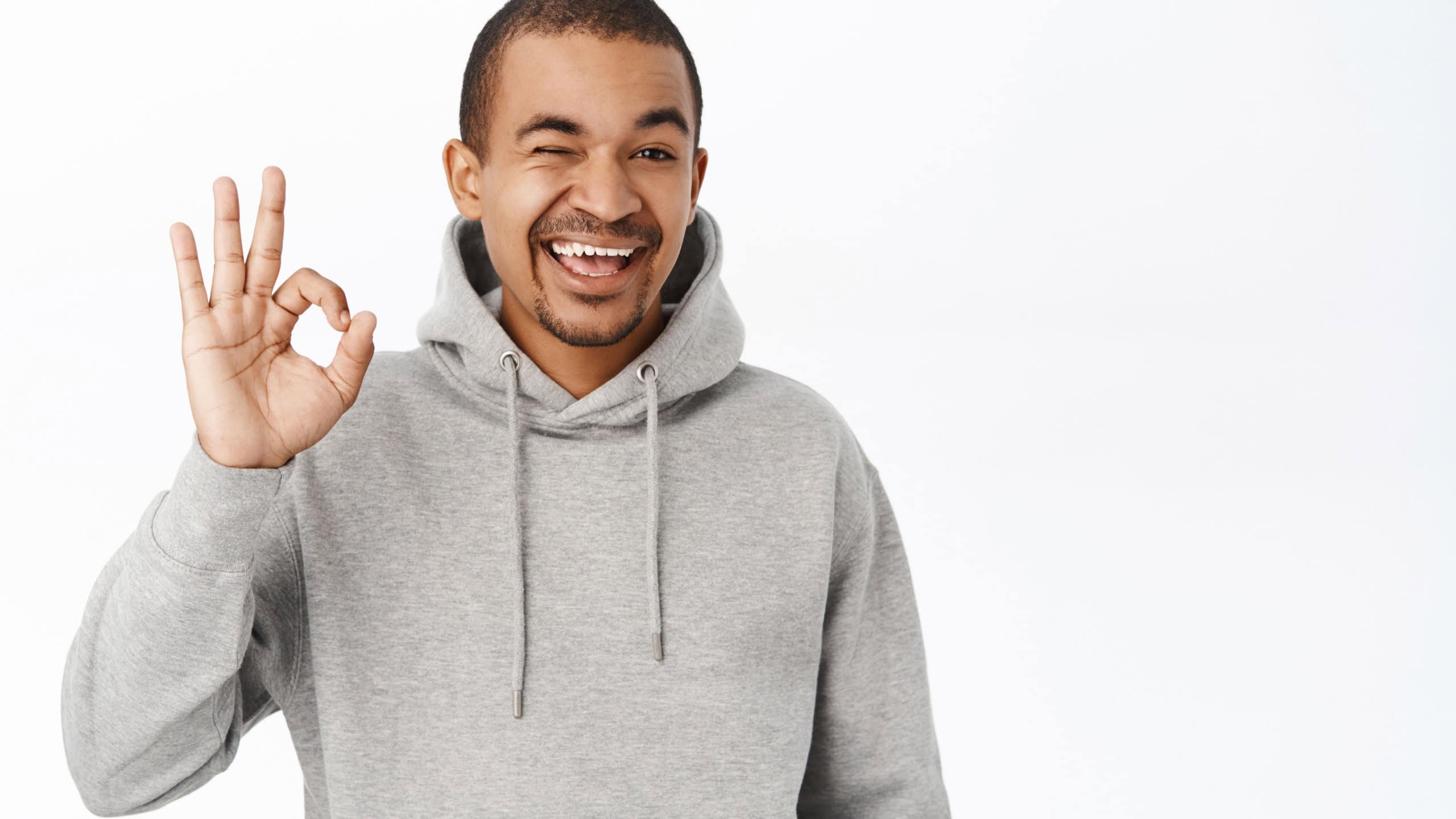 Excellent, good choice. Smiling handsome guy shows okay, ok sign, recommending smth great, complimenting, standing over white background