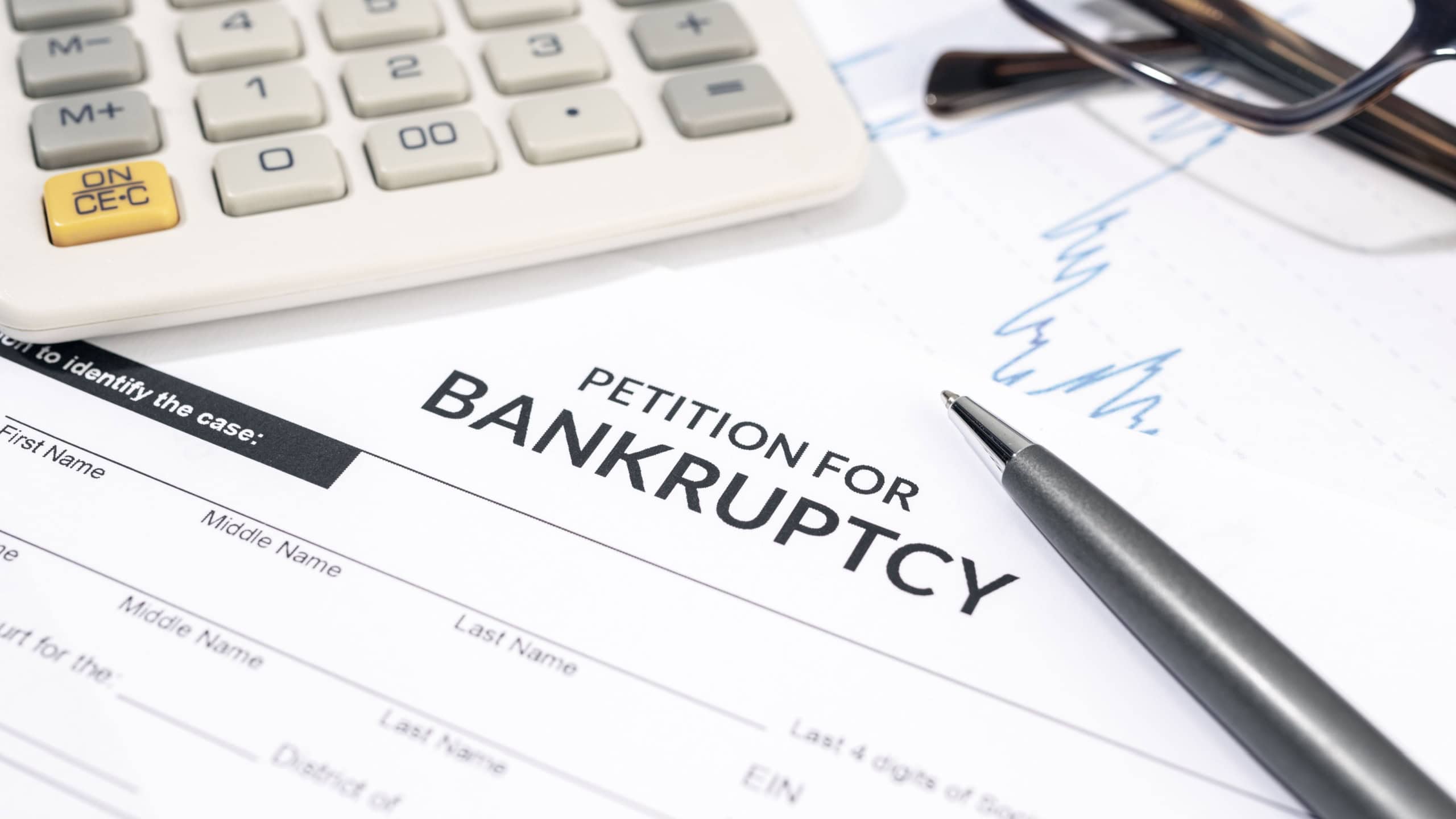 Bankruptcy form, calculator and pen on desk. Personal injury claim form
