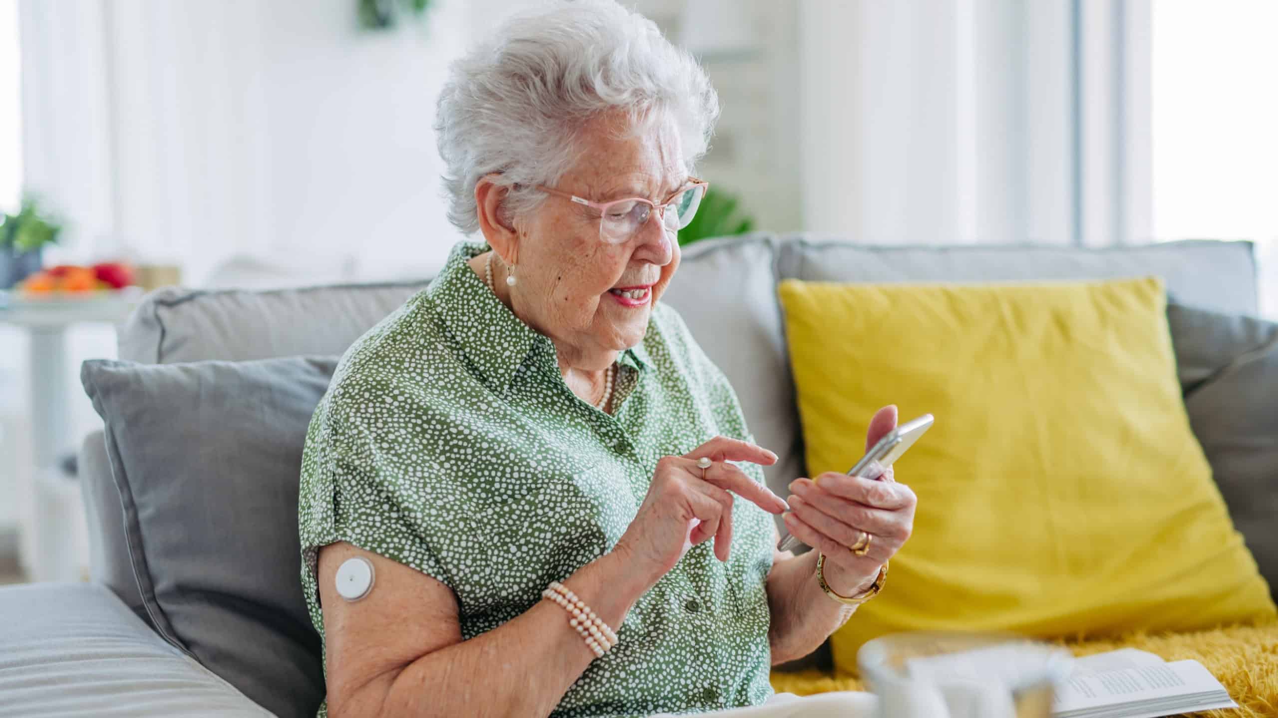 Senior diabetic woman checking her glucose data on smartphone.