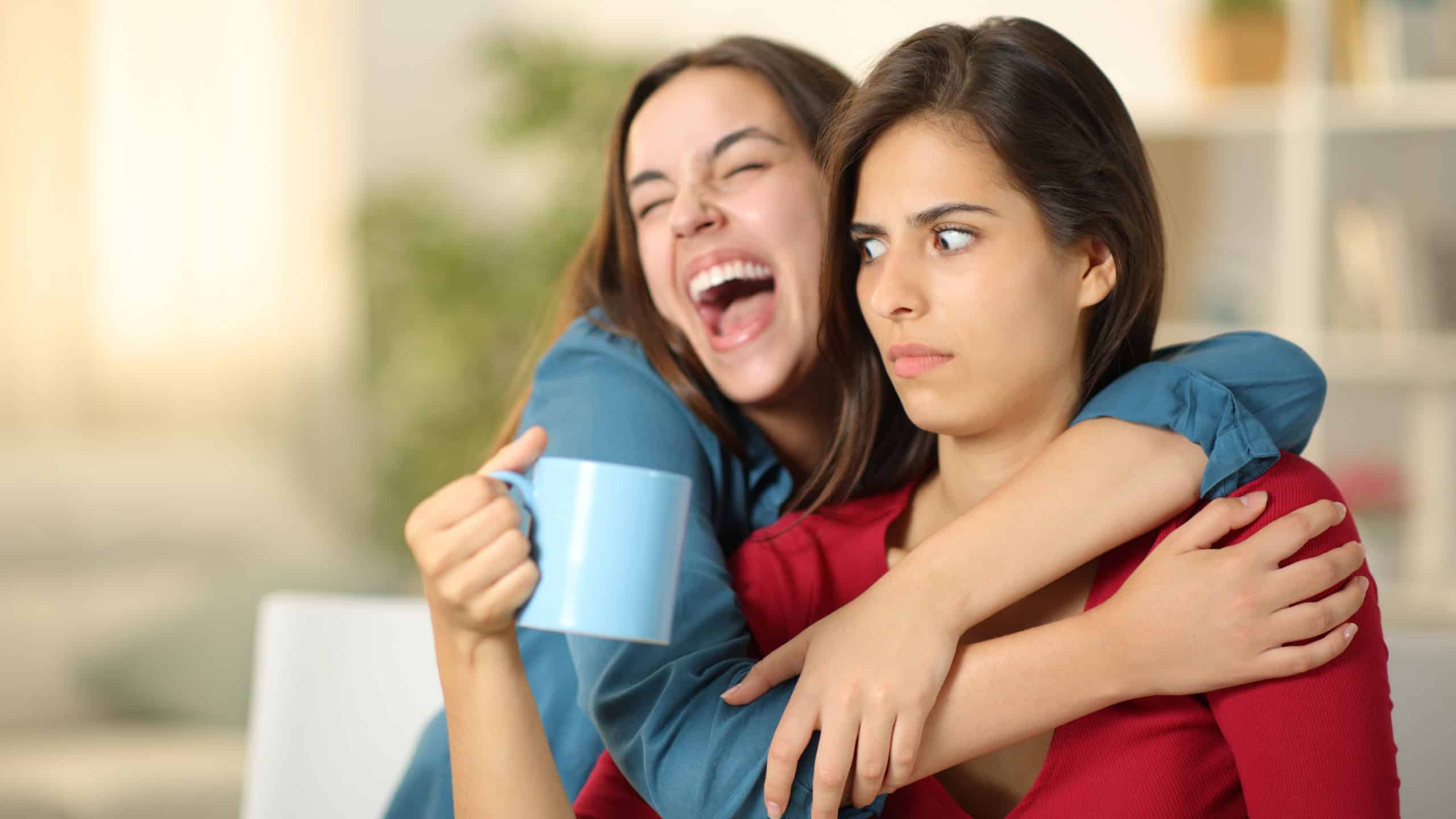 Excited woman embracing a perplexed friend at home