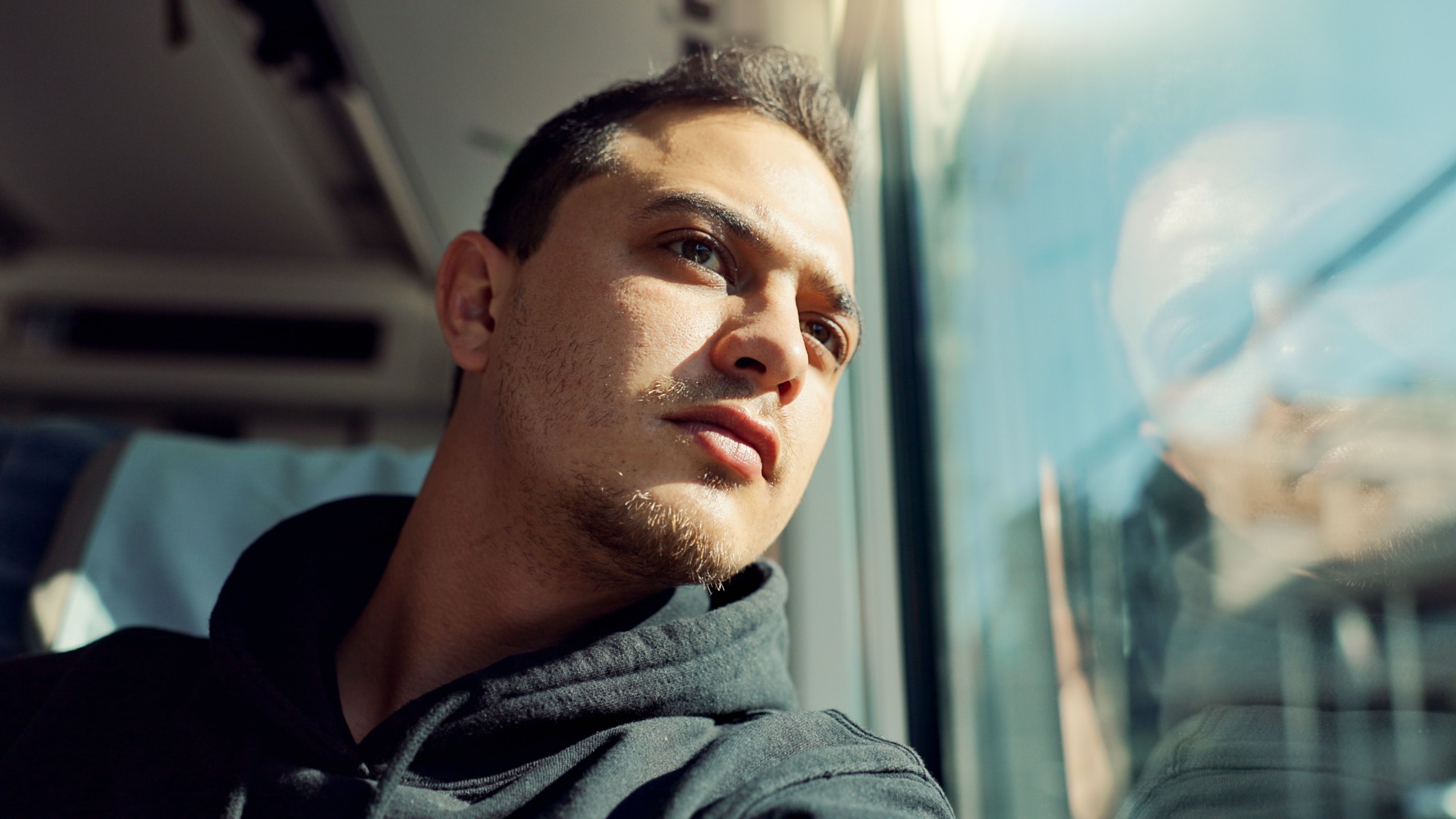 Thinking, sad and young man on train with mental health problem or loneliness on trip or journey. Depression, upset and male person from Canada on public transportation for vacation or holiday.