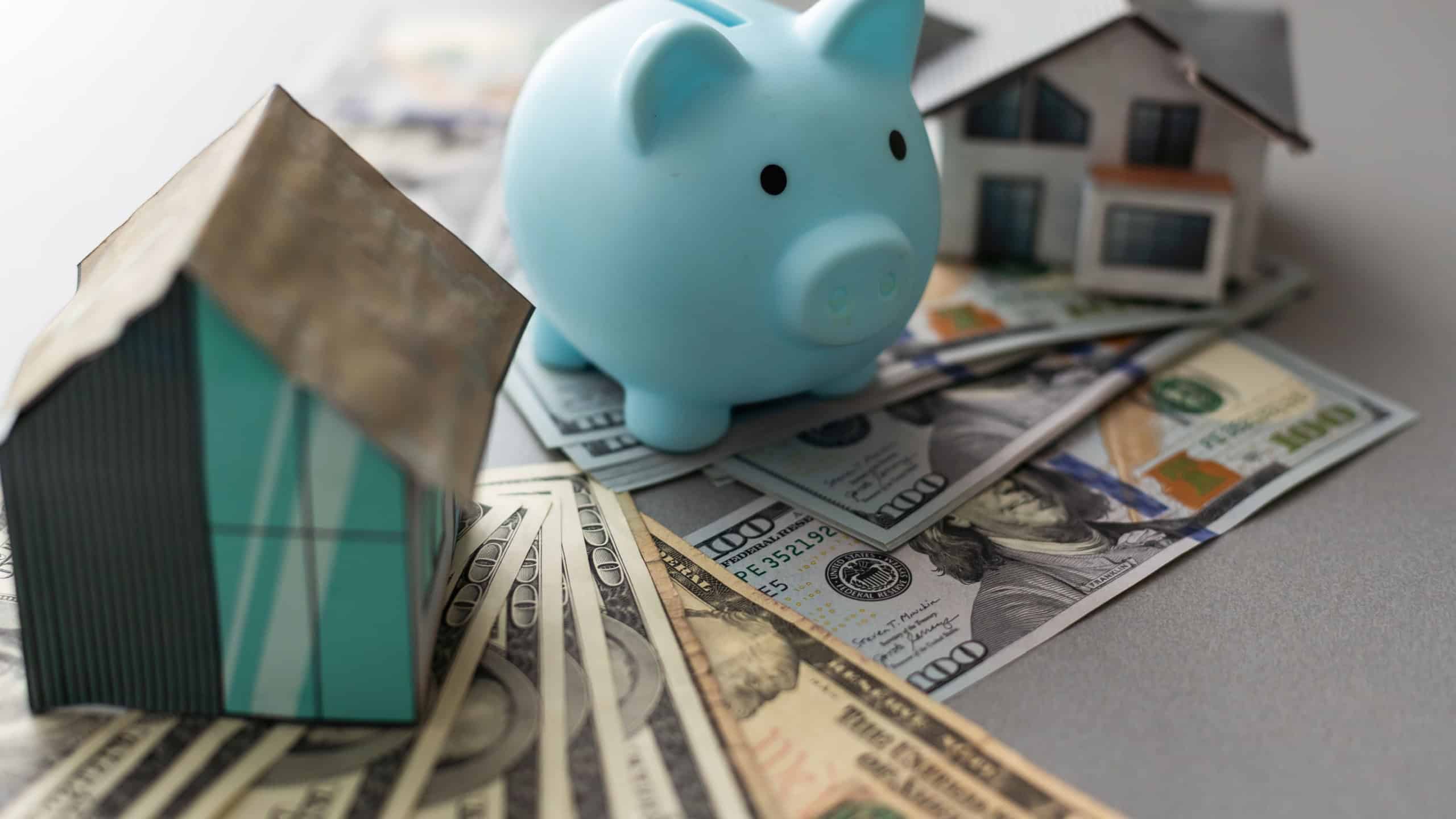 Piggy bank for money and a house model with dollars on a white background. buying a property. the concept of buying and selling houses and apartments.