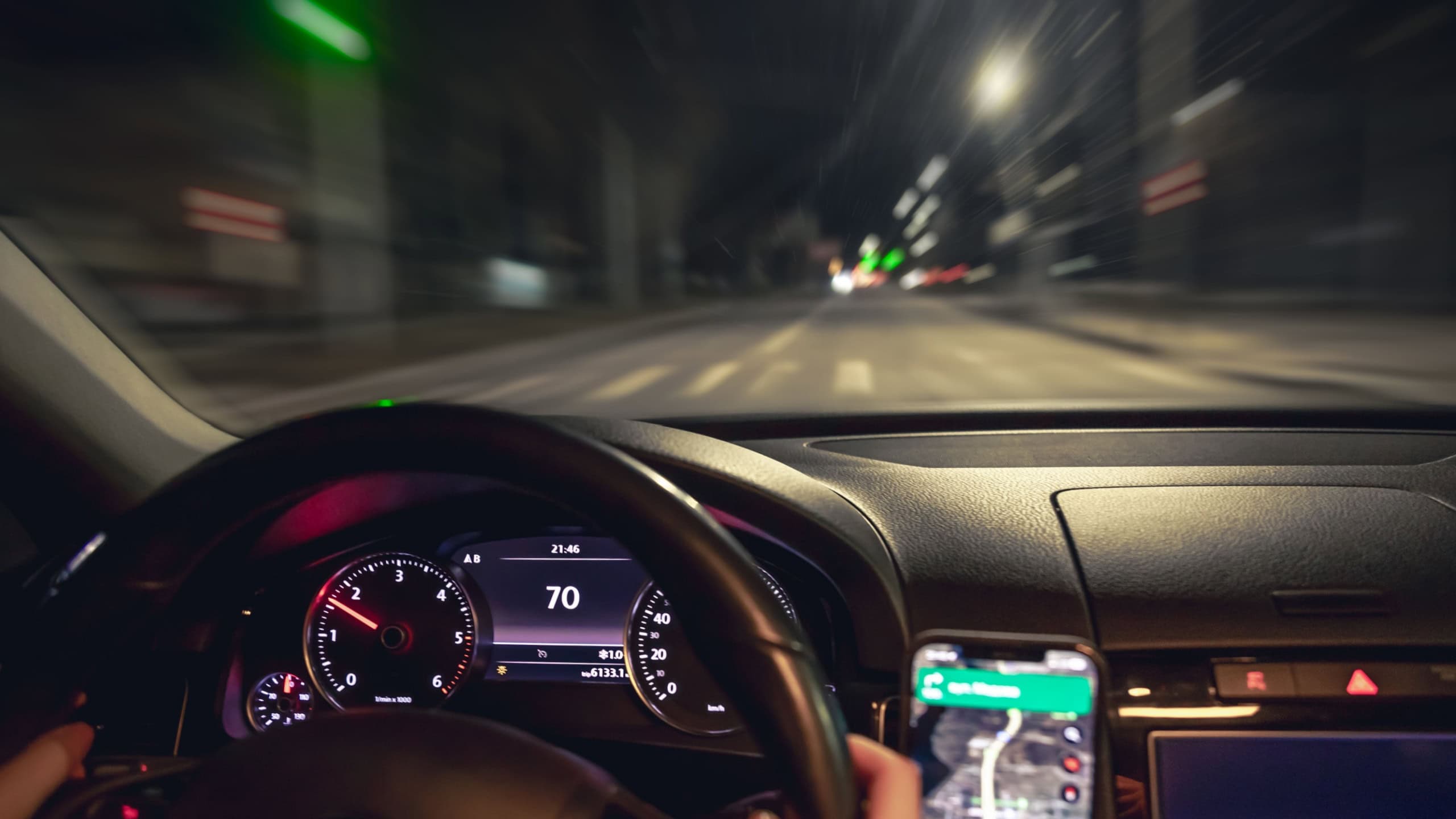 Car steering wheel and view of the night road from the car, close-up.