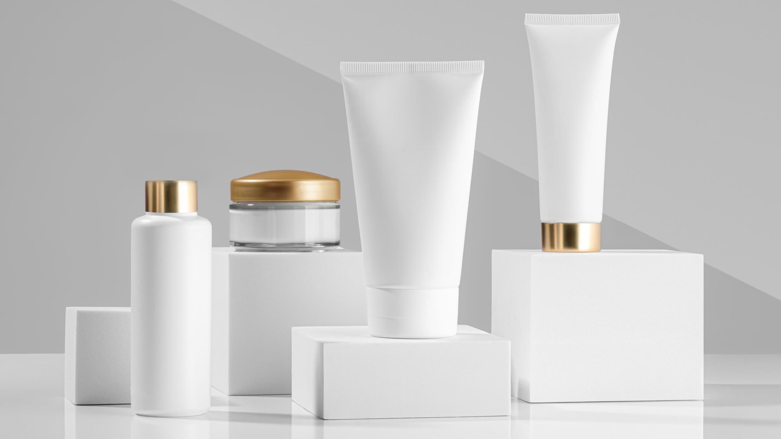 White cosmetic products for face and body on white cubes