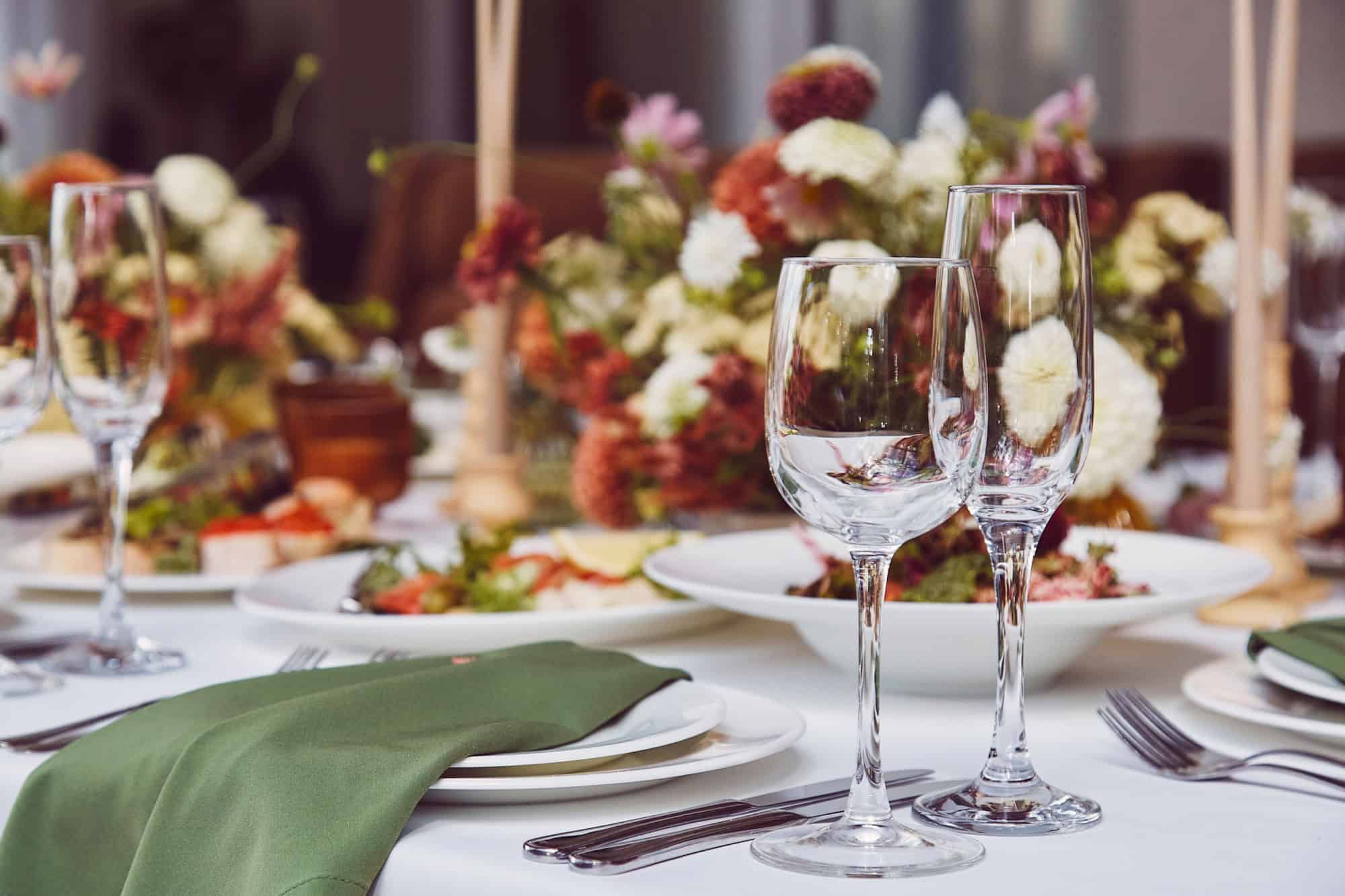 Aesthetic stylish autumn table setting background, arranged flowers and candles under natural light. Cozy holidays table setup.