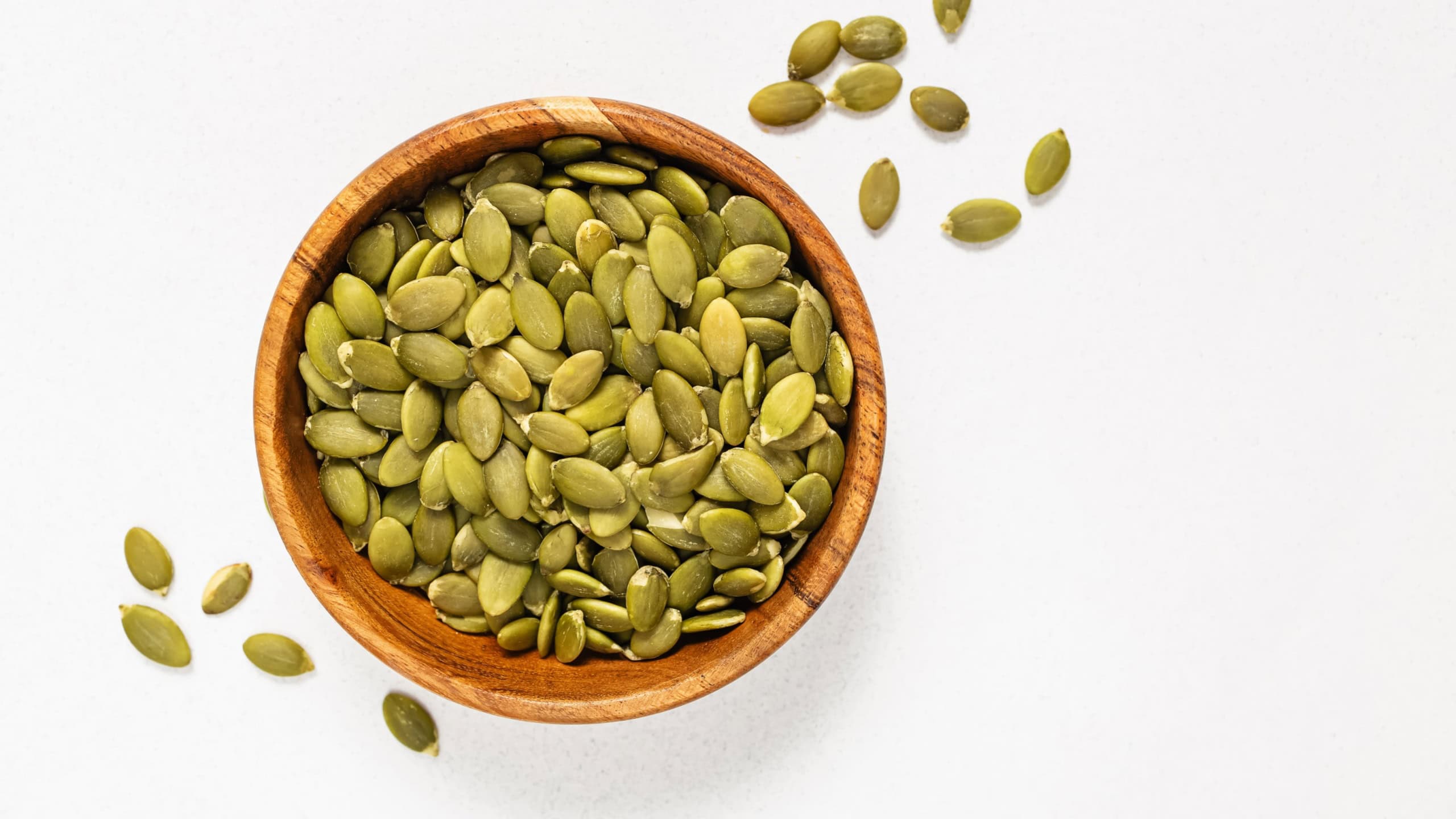Pumpkin seeds in a wooden bowl, view from the top