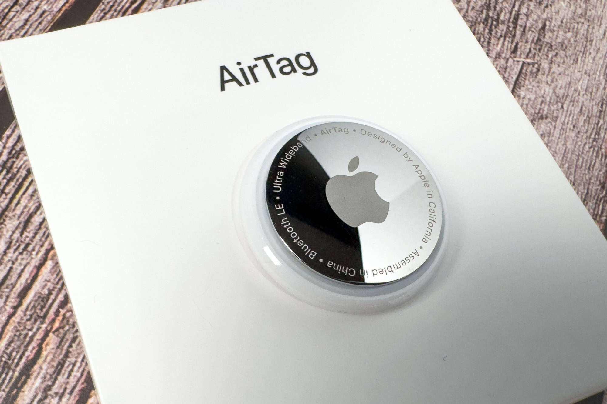 Jurmala, Latvia - 22 September 2024 An Apple AirTag is showcased on its packaging, highlighting the sleek design and modern technology. The setting features a textured wooden table.