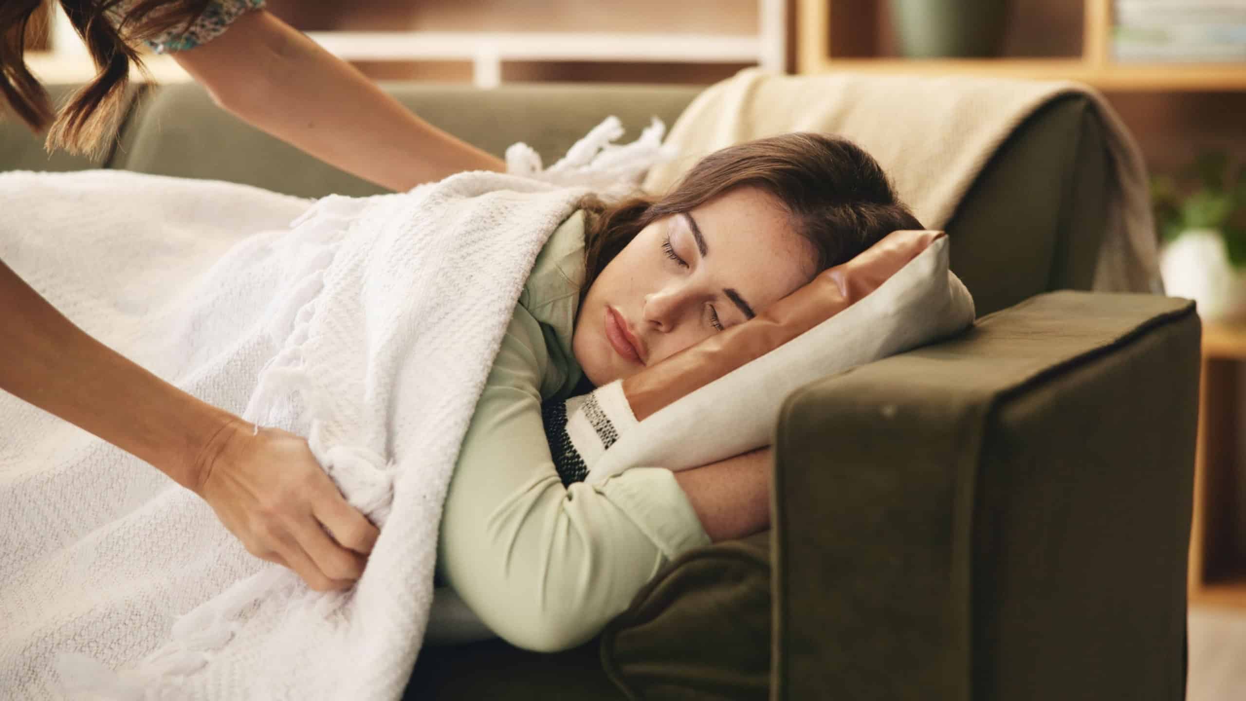 Sleeping, tired and woman on sofa with blanket for resting, dreaming and nap in home. House, living room and mom with person with duvet, pillow and comfortable for relaxing on couch on weekend