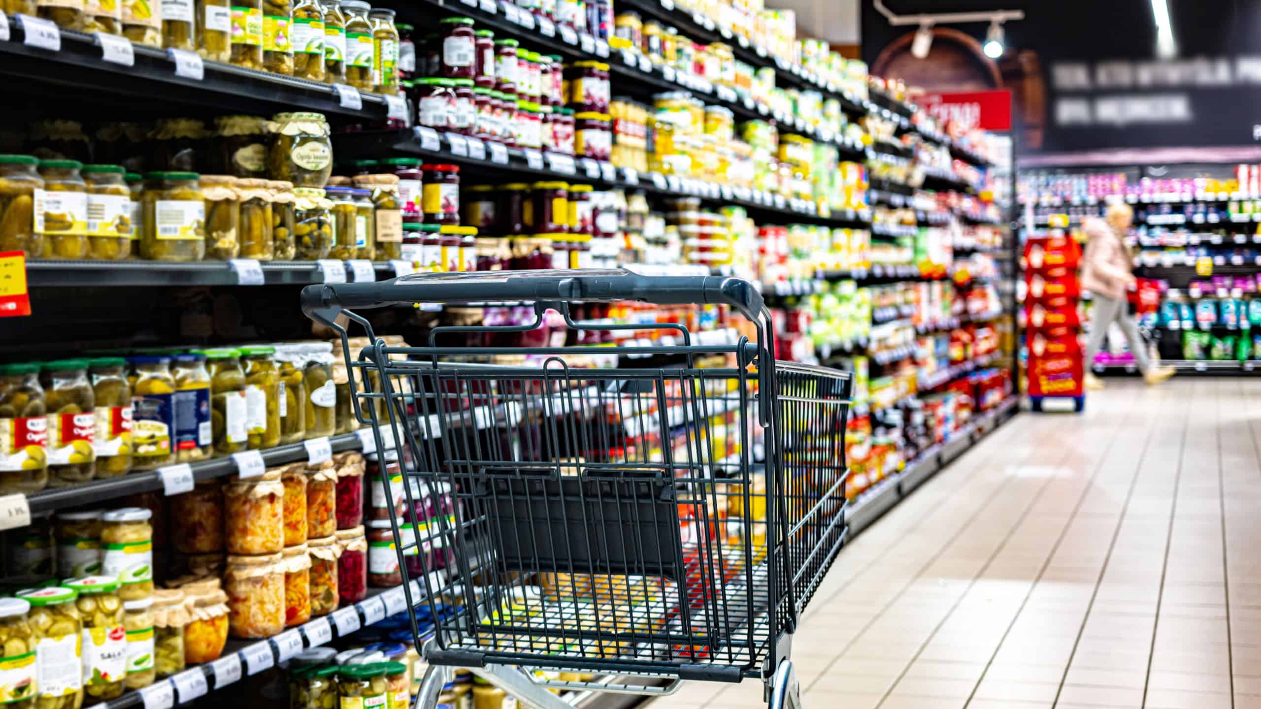 A shopping cart by a store shelf in a supermarket