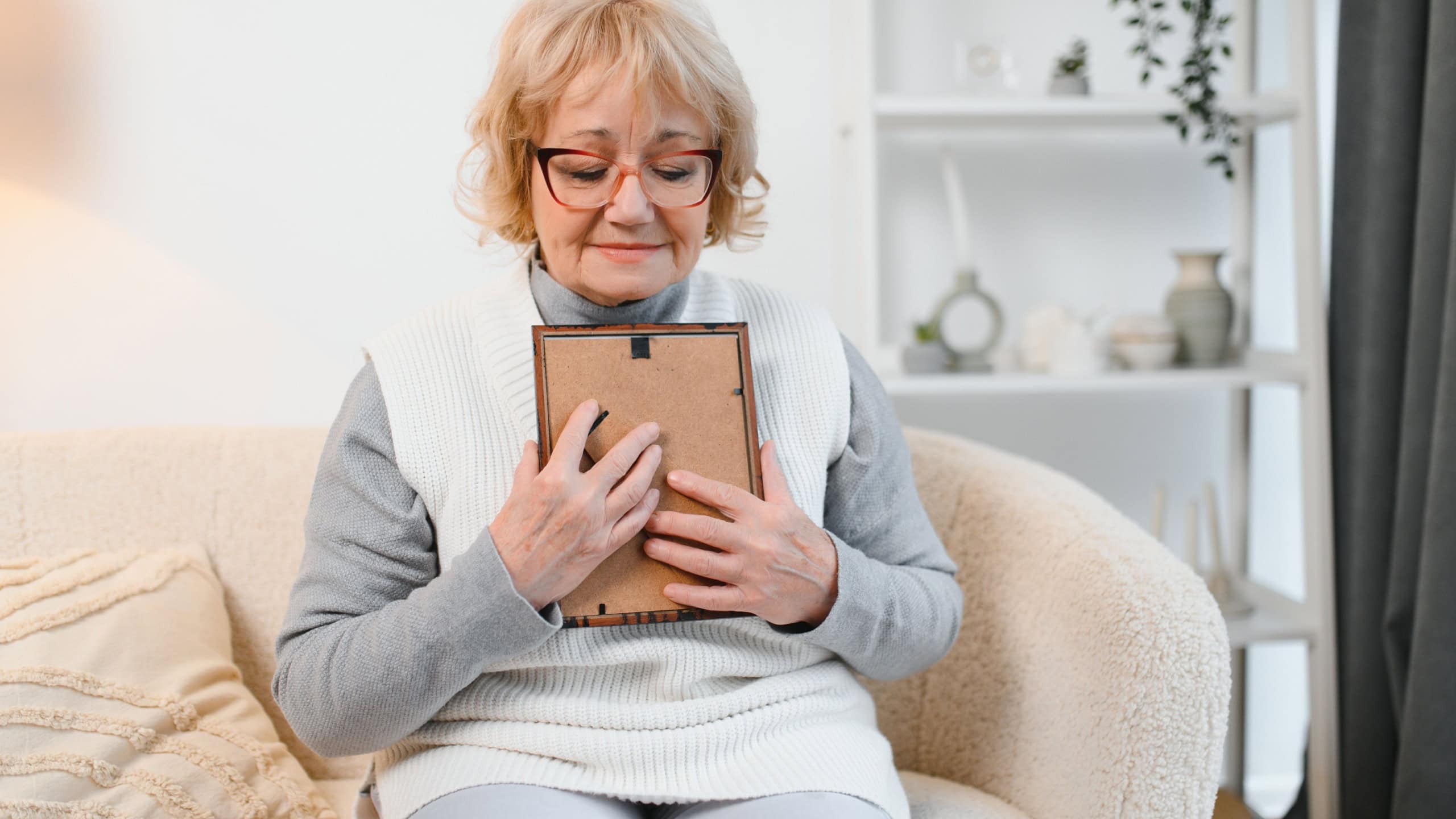 Elderly woman looks at photograph with nostalgia