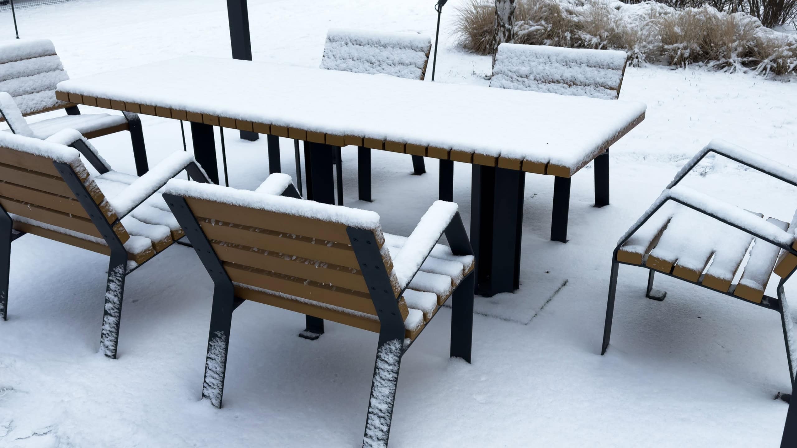 Outdoor furniture is covered with snow in a winter. Winter patio and garden during snowfall. Nobody, street photo, selective focus