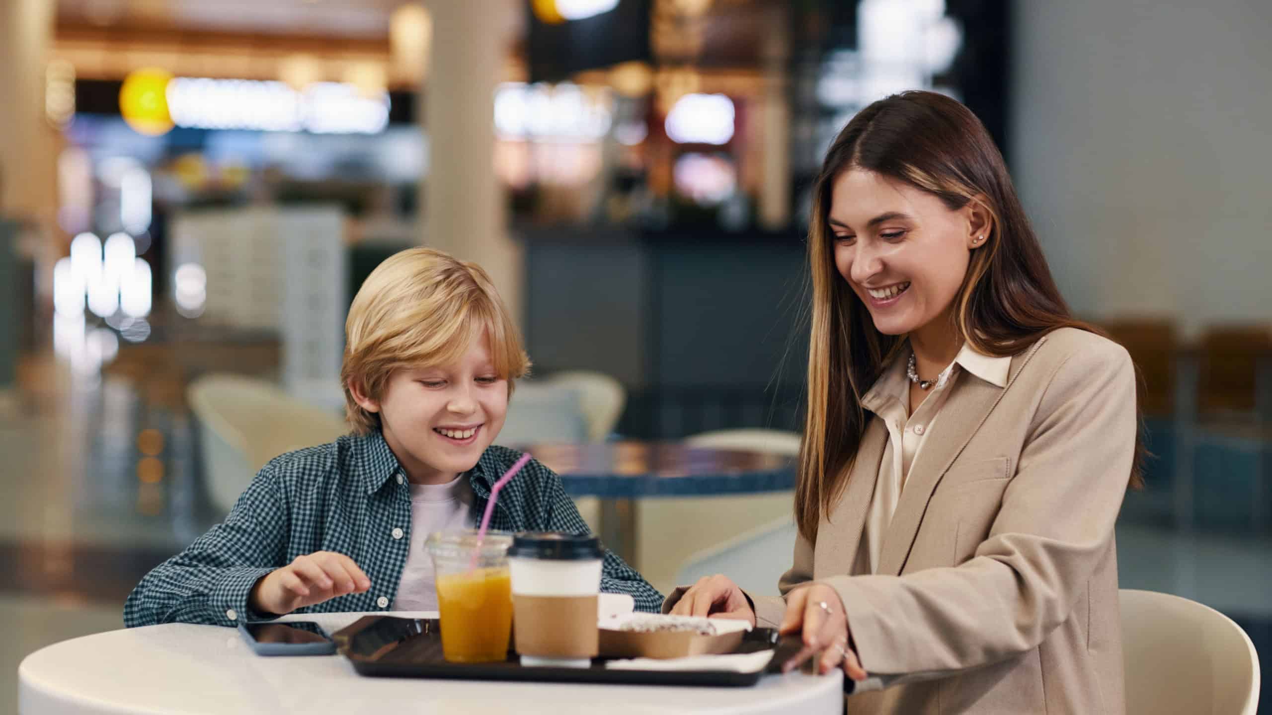 Medium shot of brunette mom taking tray full of beverages and hot delicious food to have lunch after shopping