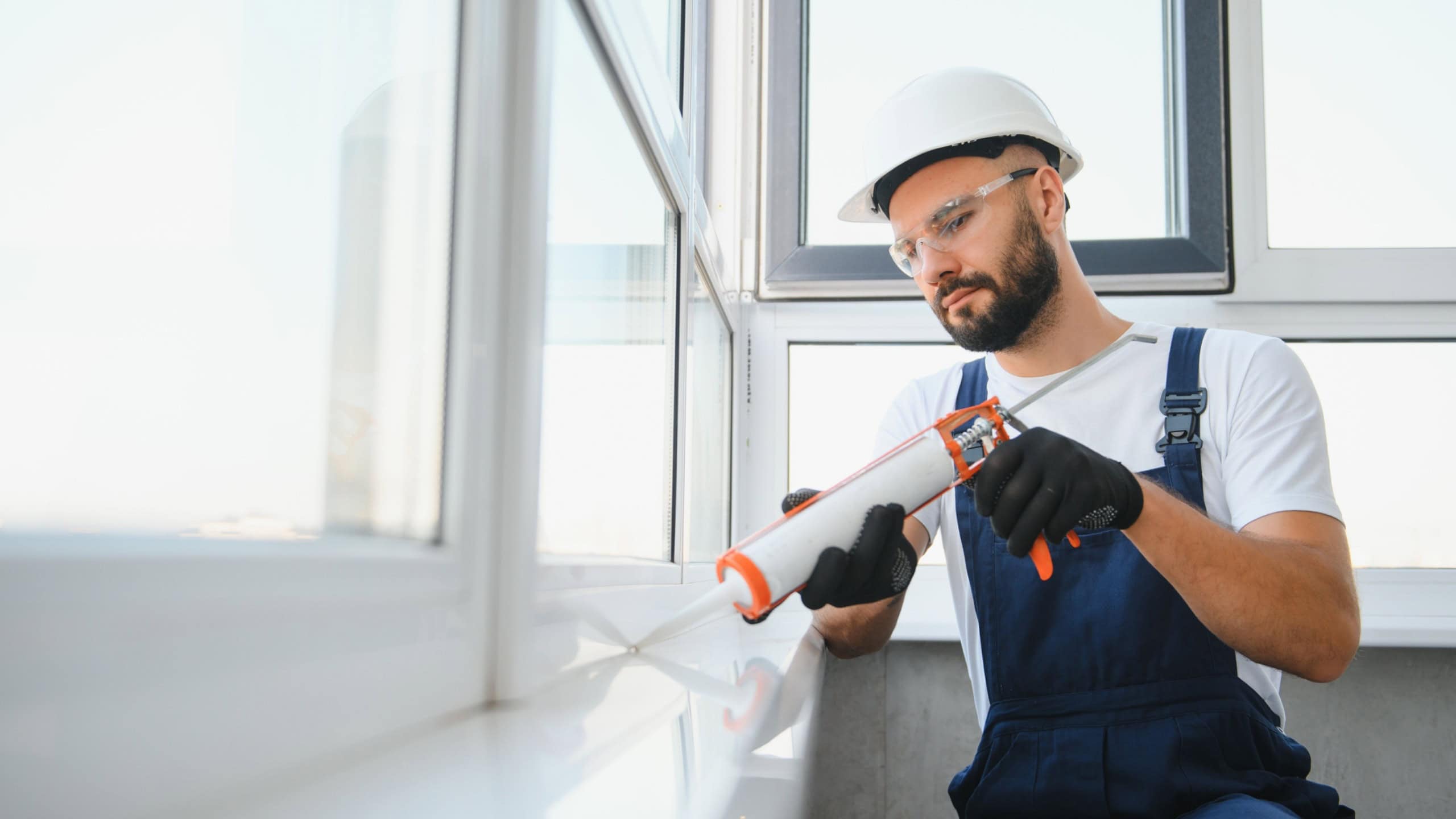 Hands applying silicone sealant that defending from water leaks and mildew. Home repair and maintenance services.
