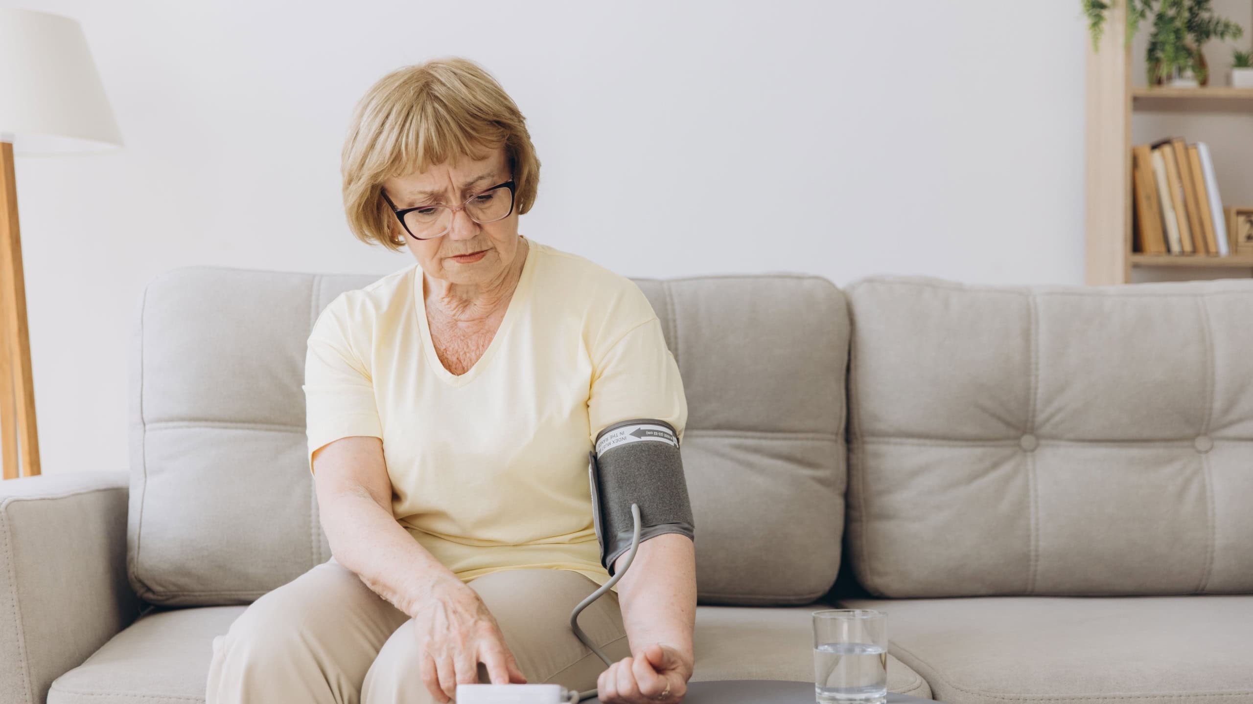 Senior woman with hypertension measuring blood pressure herself at home. Sad Elderly lady measure blood pressure using tonometer. Everyday health check-up