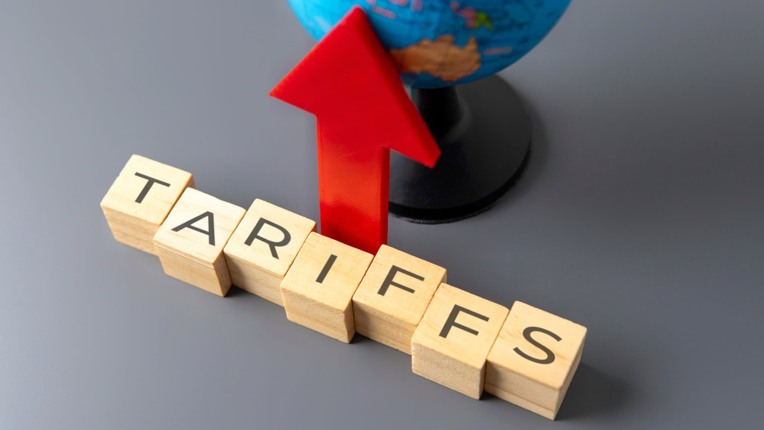 Upward pointing arrow and wooden blocks with word TARIFFS. Increasing tariffs in global trade concept.