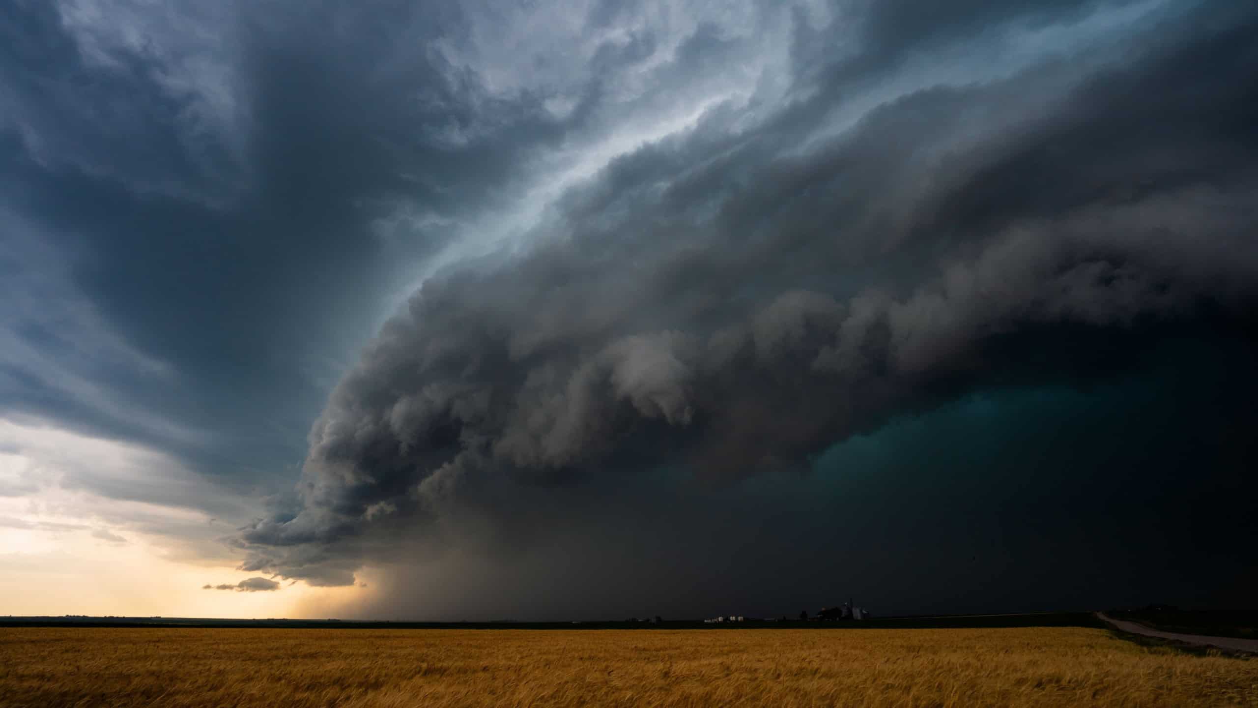 Massive thunderheads tower over a windswept prairie, their dark, dramatic sky filled with texture, stormy shadows, and epic beauty in nature, capturing the power of weather and atmosphere