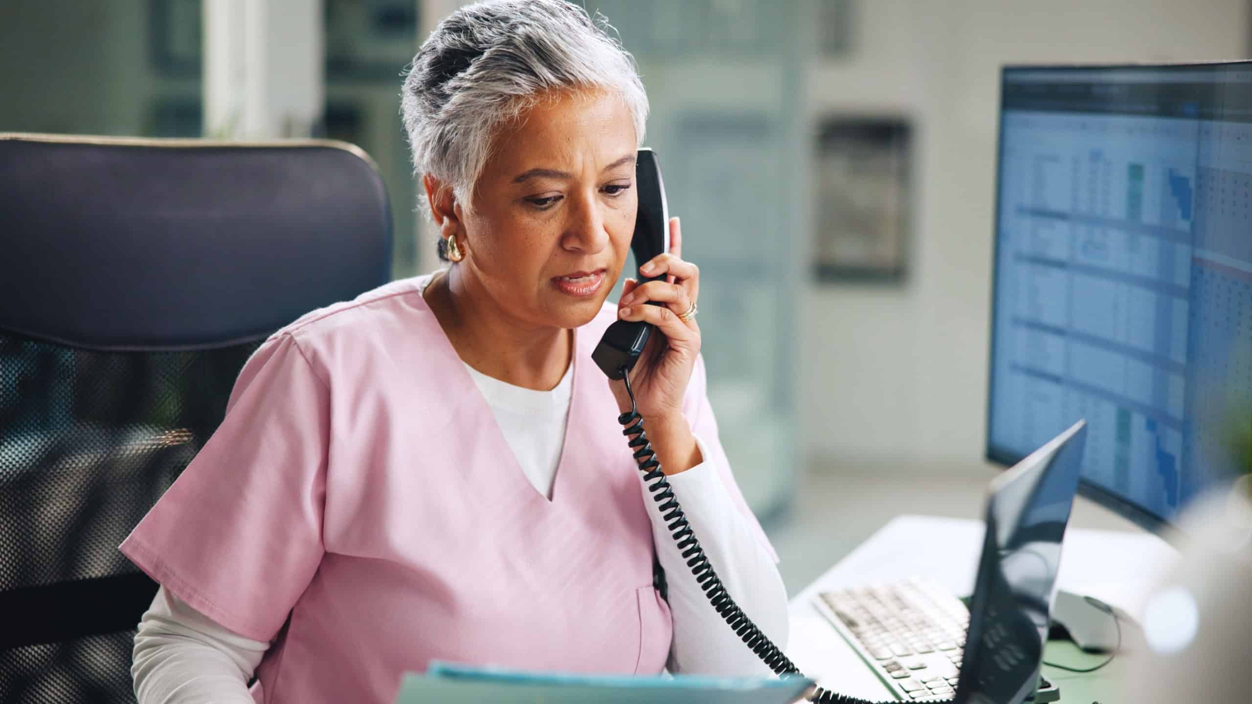 Woman, nurse and phone call in hospital with folder, medical information and update appointment. Healthcare, mature clinical assistant and talk at tech for oncology schedule, cancer referral and help