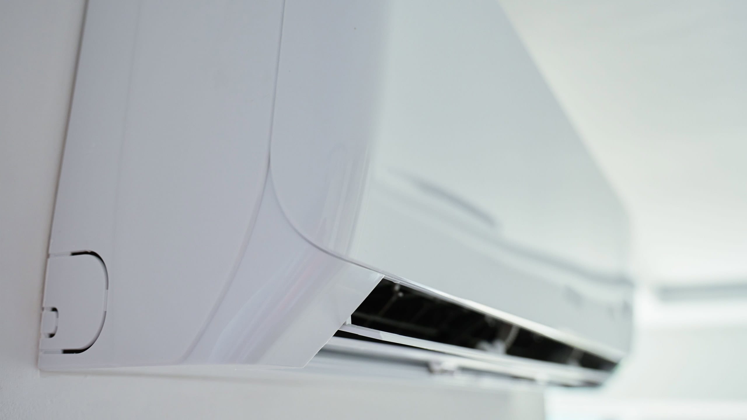 Close-up view of modern air conditioning unit mounted on white wall in bright room. Home cooling technology, climate control, energy efficiency and comfort in hot weather