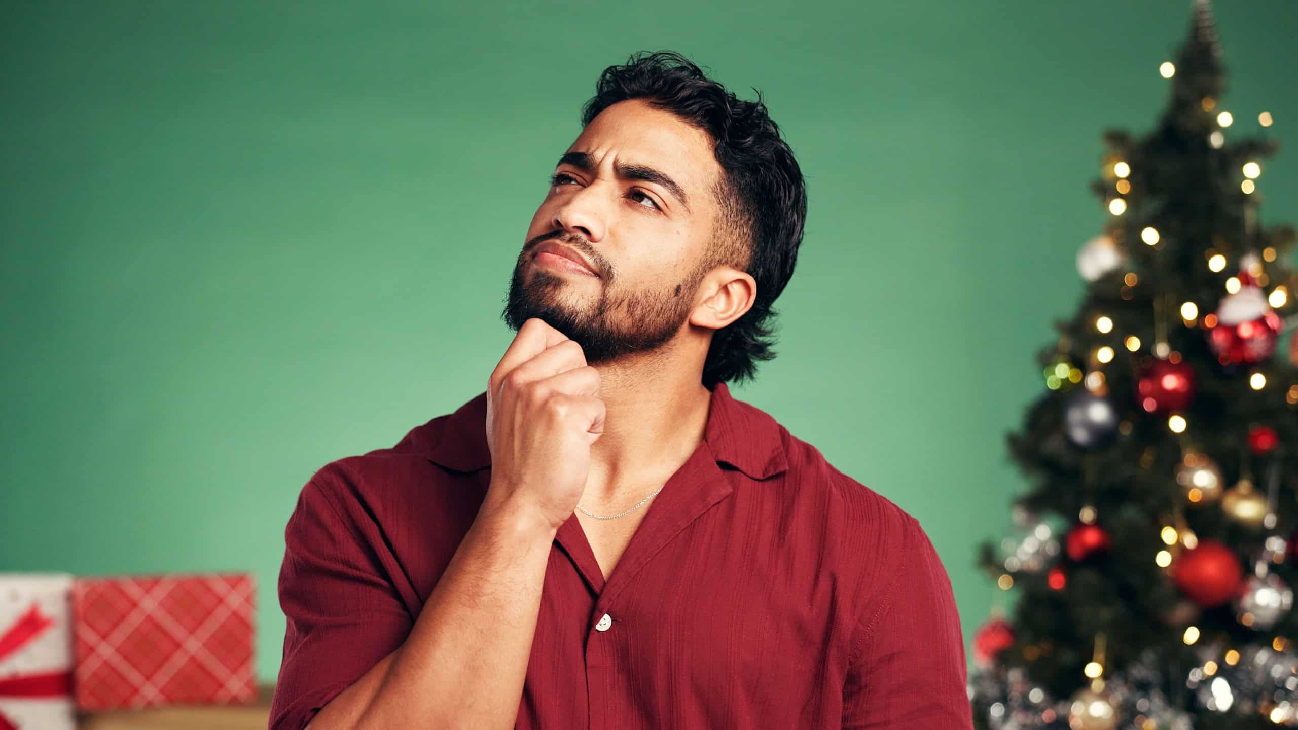 Christmas, thinking and reflection with man in studio for decision, holiday season and gift planning. Festive tradition, future and space with person on green background for inspiration and vision