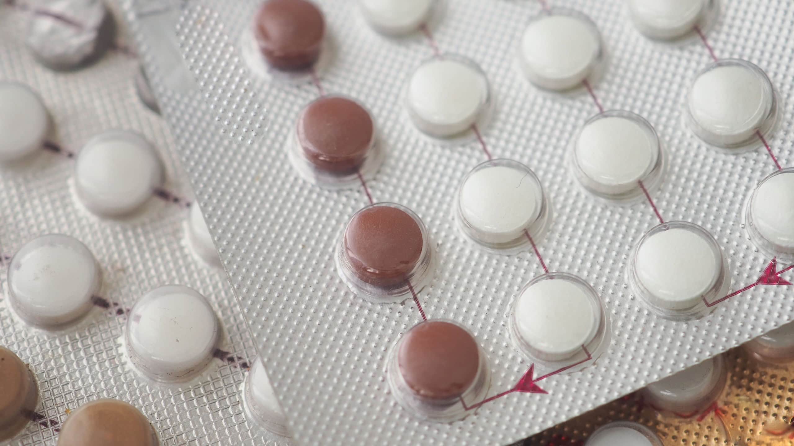 Different colored birth control pills in organized blister packs
