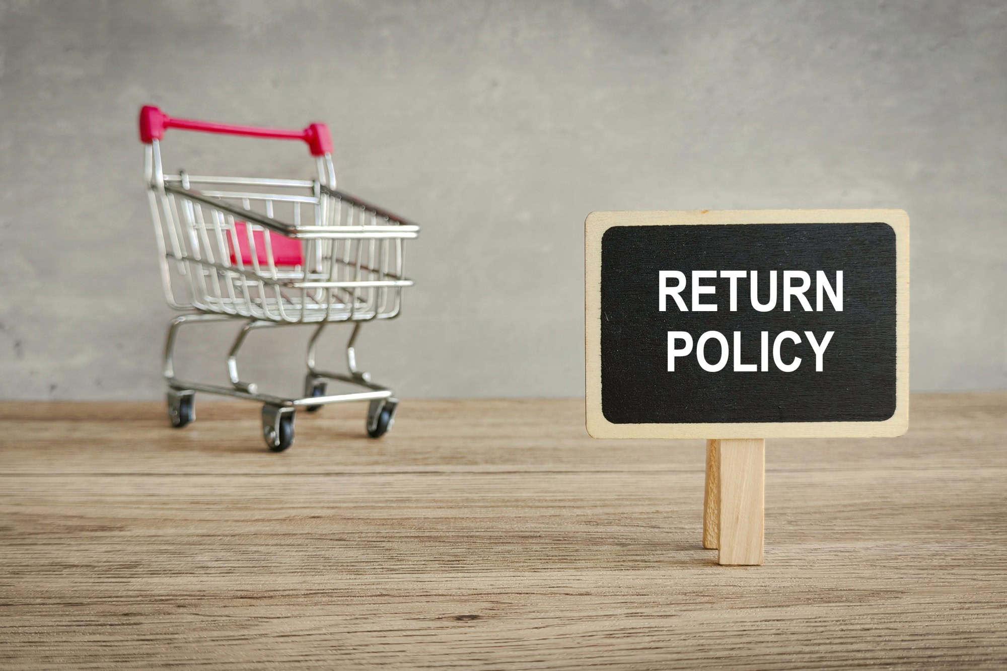 Return Policy or Guarantee Concept: Shopping Cart and Signboard on a Rustic Wood Table Emphasizing Customer Protection.