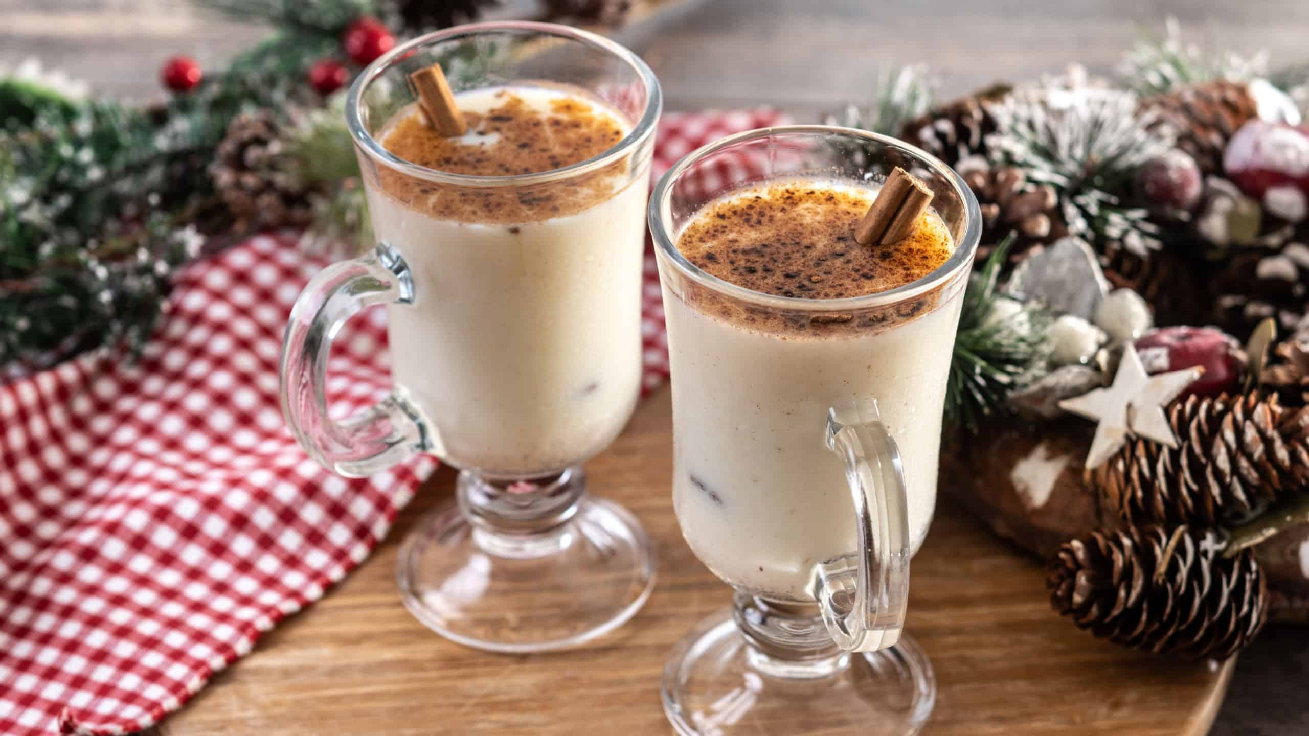 Eggnog with Cinnamon and Christmas Decorations on wooden table