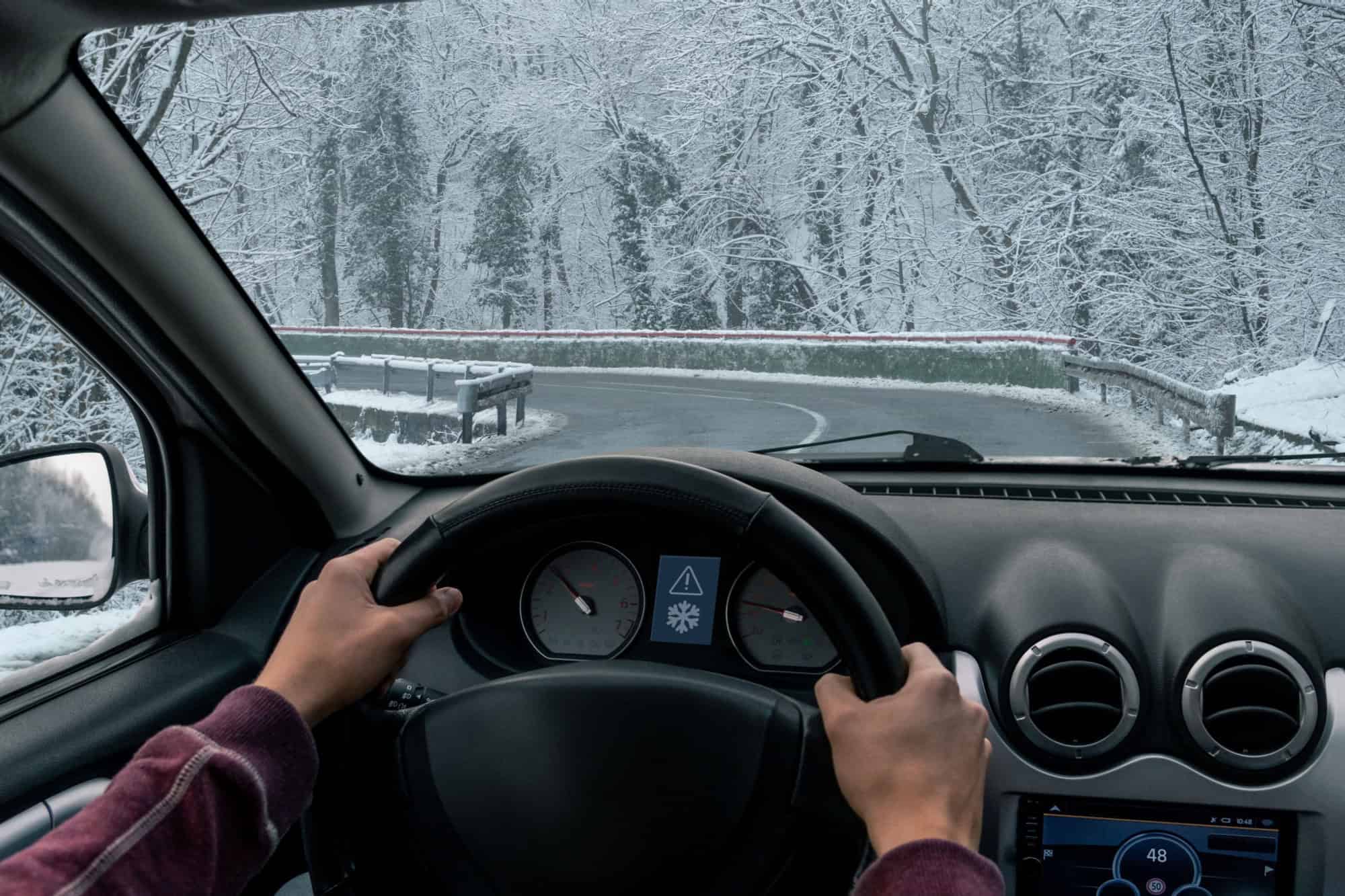 A man drives a car on a winter road in a blizzard