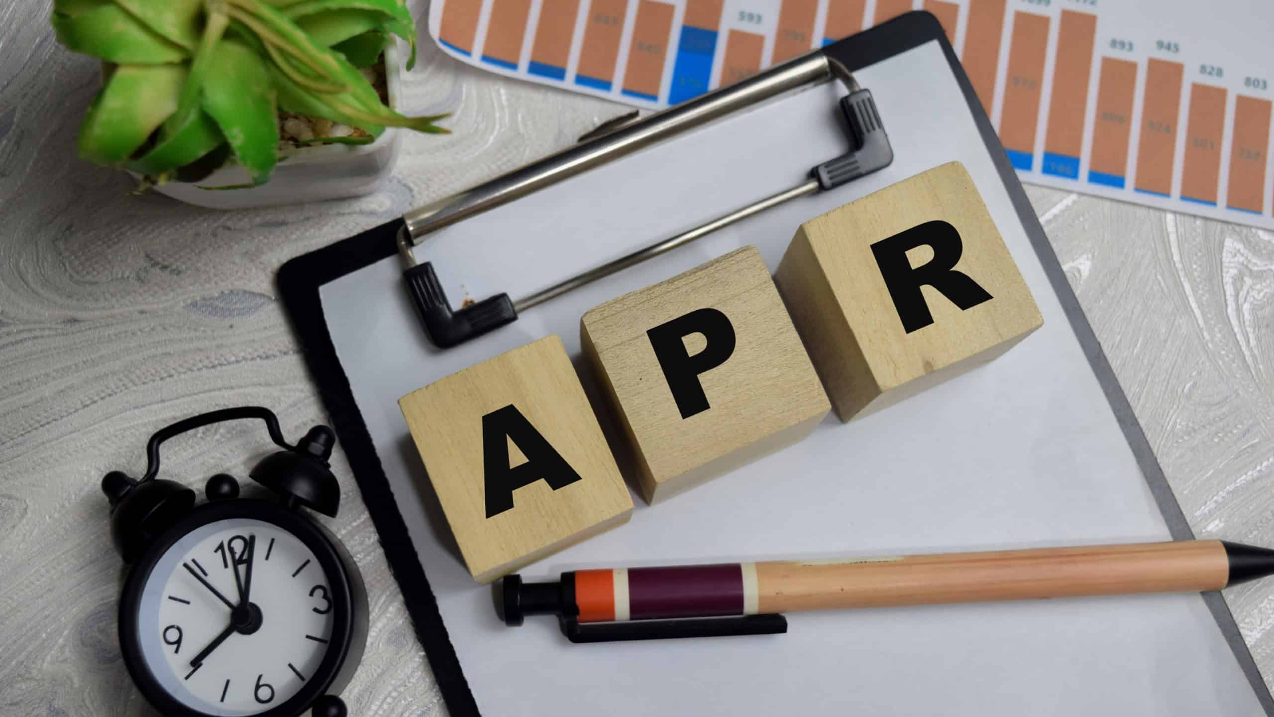 Annual Percentage Rate stacked wooden cubes with financial graphs on the table