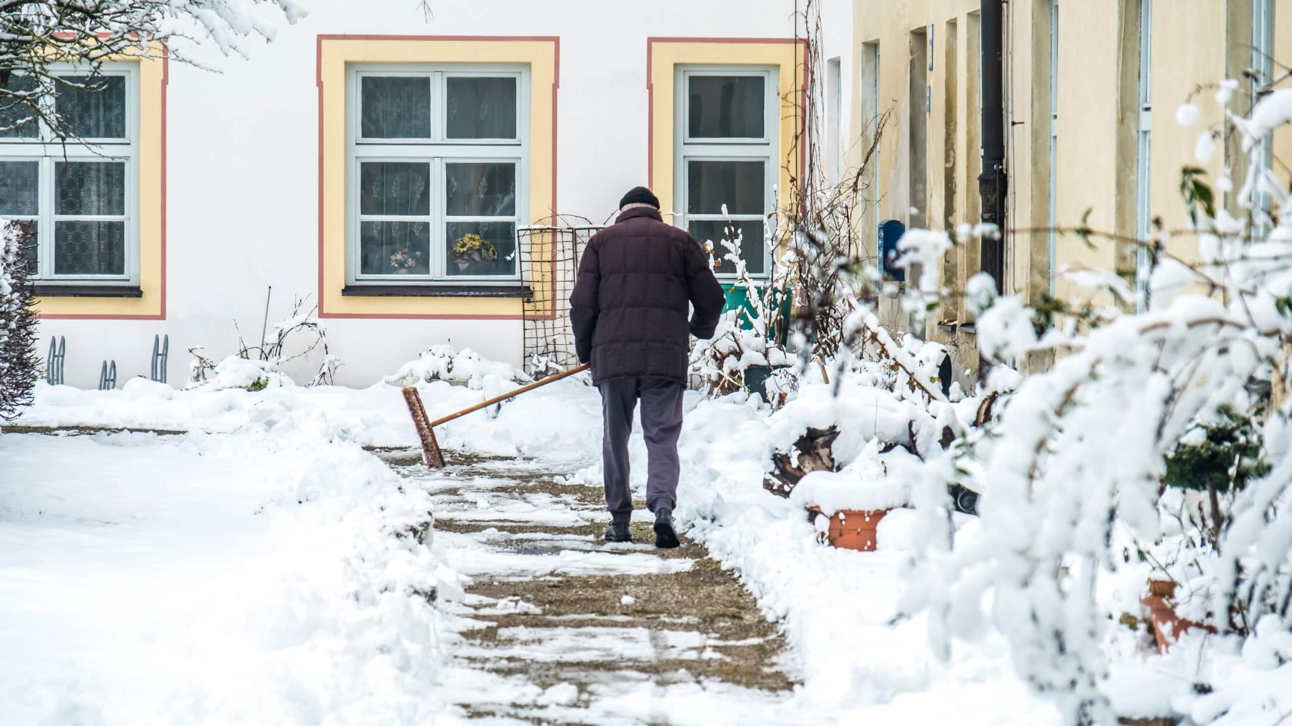 Man sweeping snow from the pavement after the storm