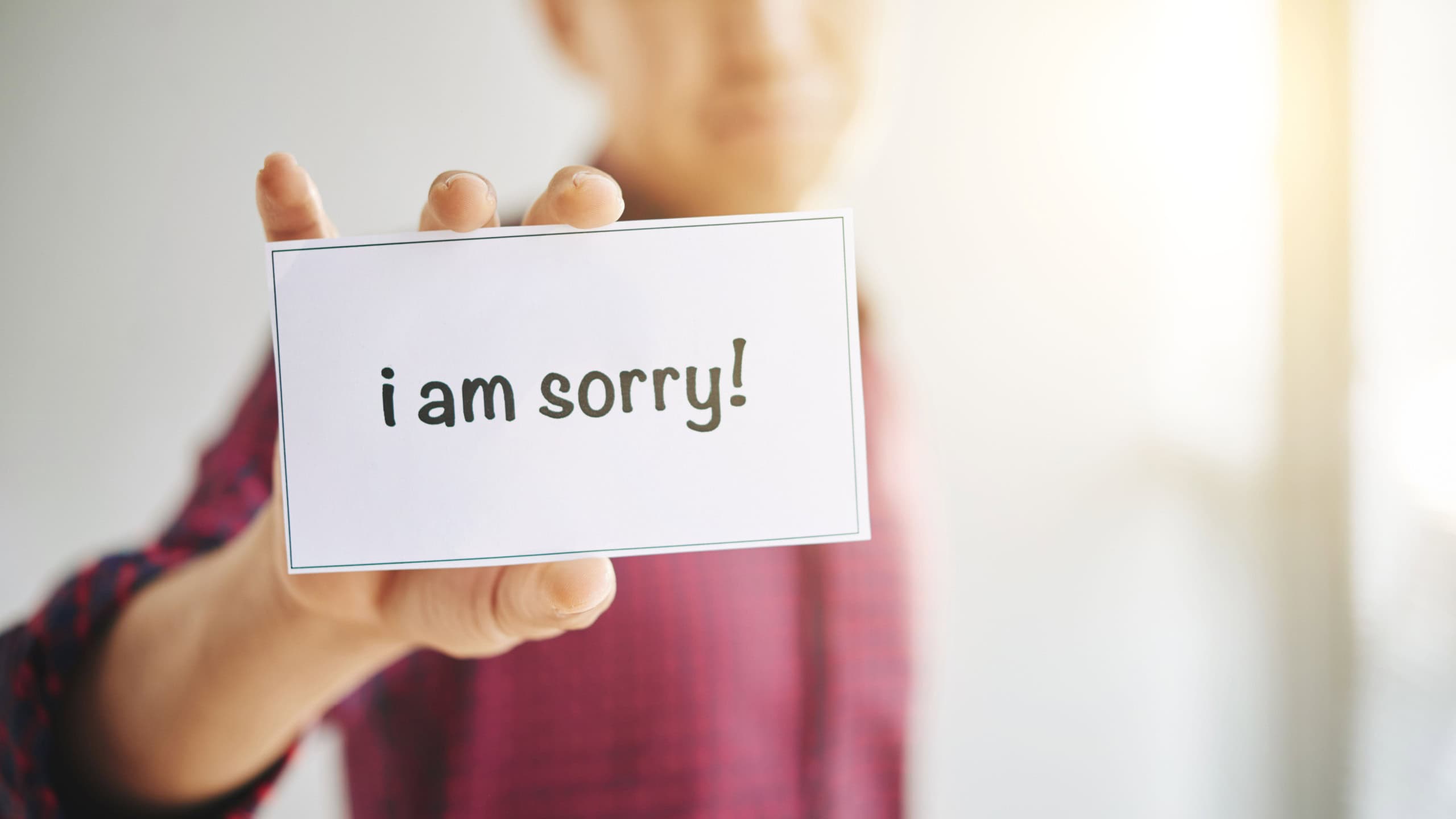 Crop male wearing checkered shirt?with I Am Sorry sign in hands