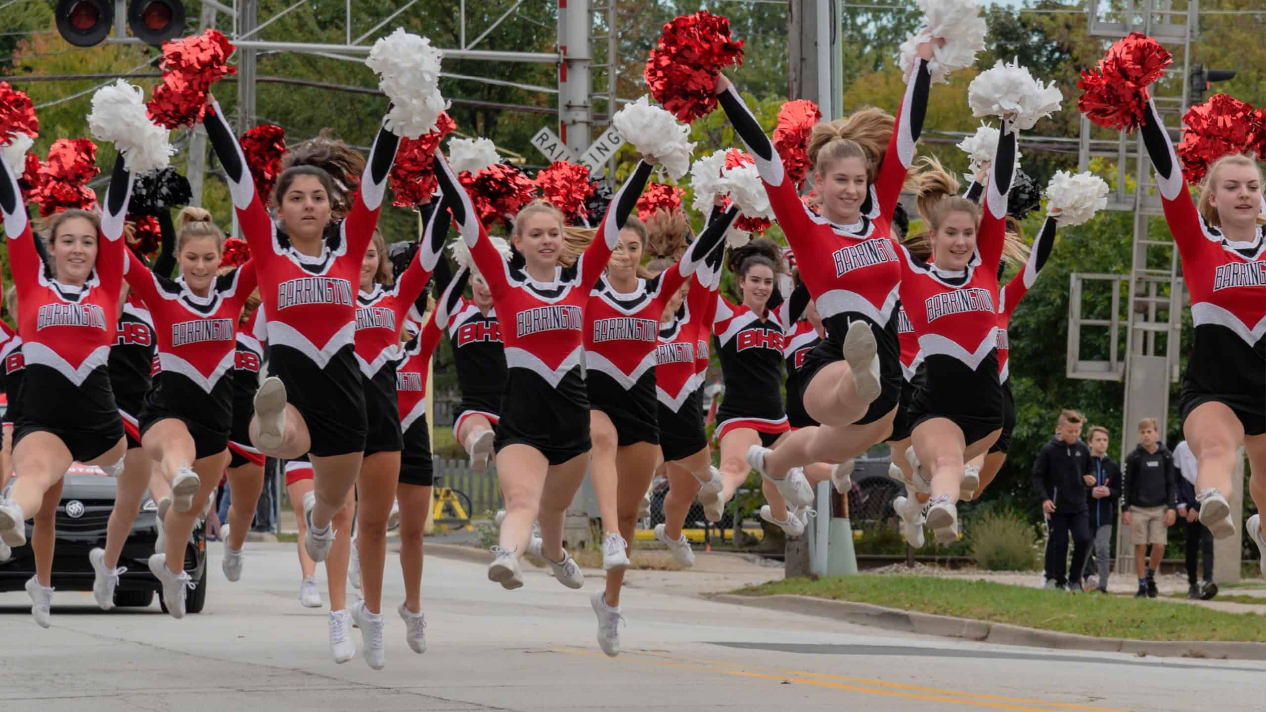Barrington, IL/USA - 09-29-2018: High school pom pom girls showing school spirit performing in homecoming parade, jumping action shot