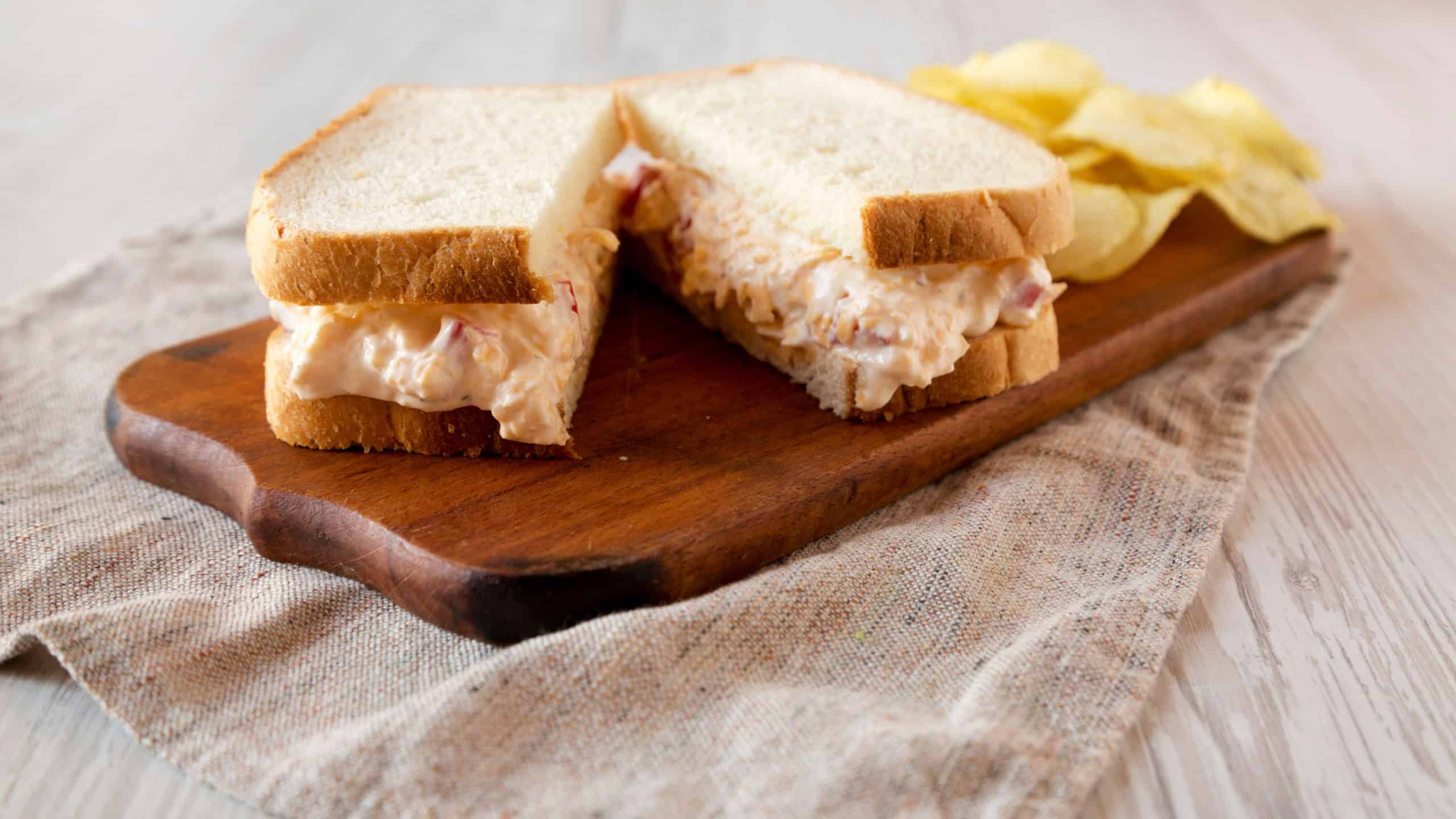 Delicious Homemade Pimento Cheese Sandwich with chips on a rustic wooden board, low angle view. Close-up.