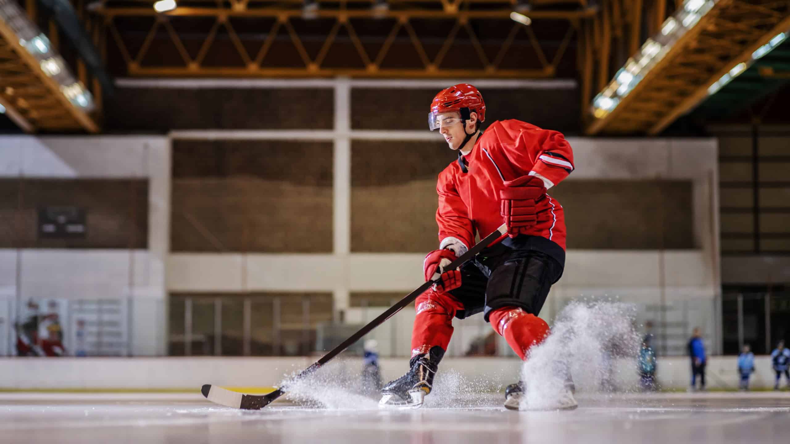 Full length of caucasian hockey player playing hockey on ice in hall.