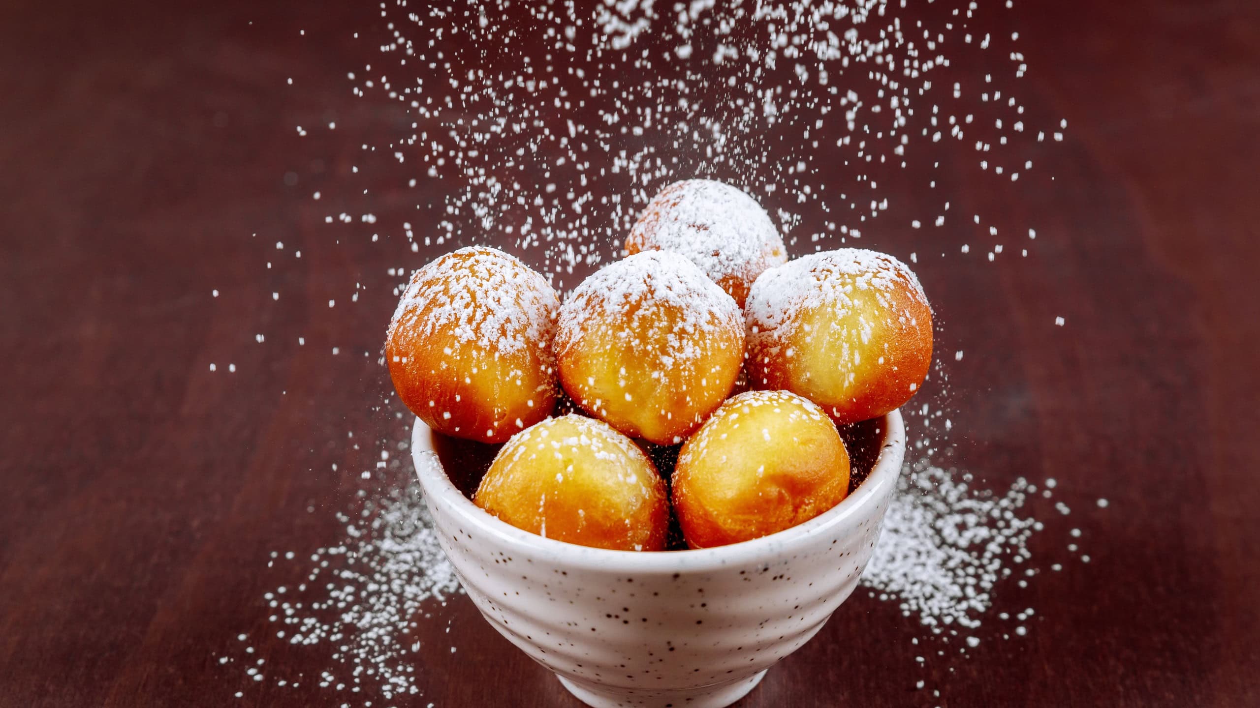 Powdered homemade munchkins ball in white plate.