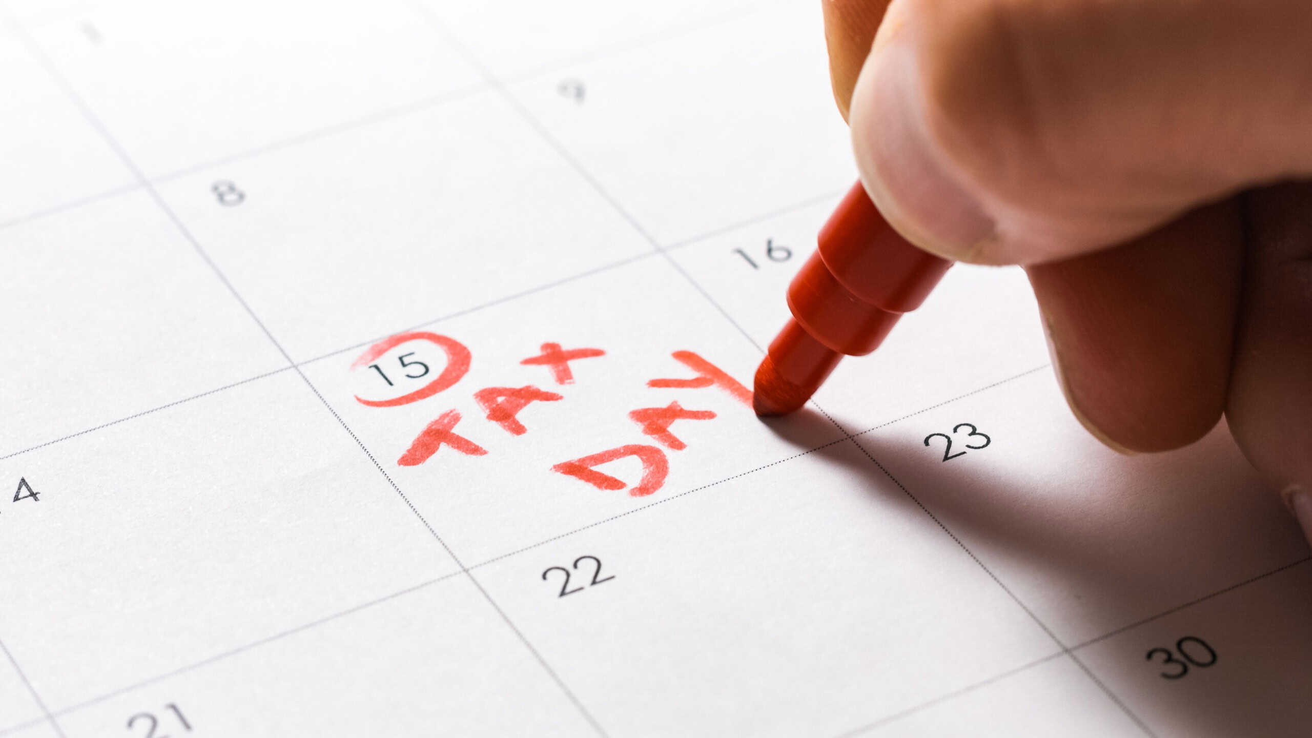 Circling April 15 and writing Tax Day in red on calendar.