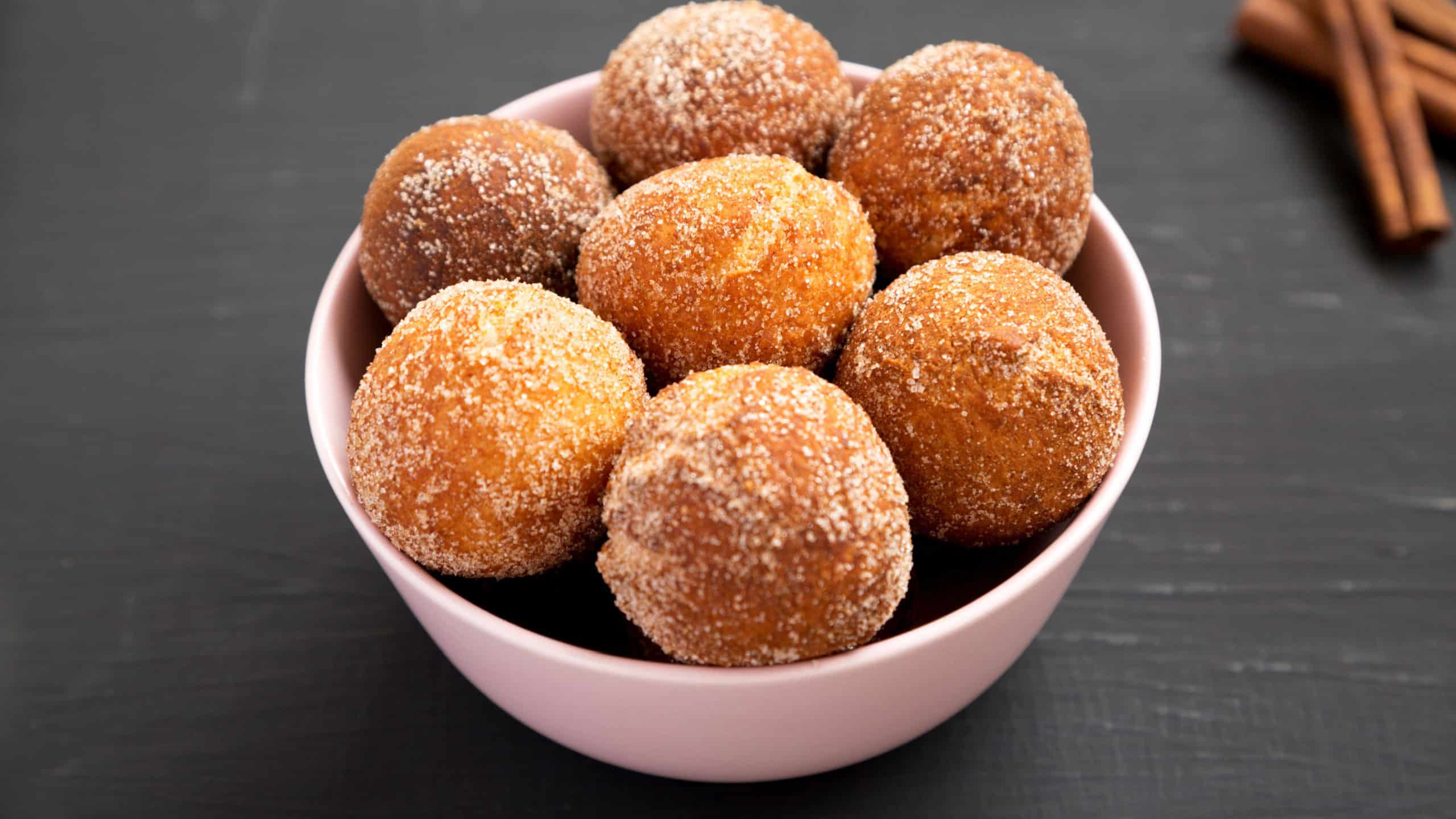 Homemade Fried Donut Holes in a pink bowl on a black surface