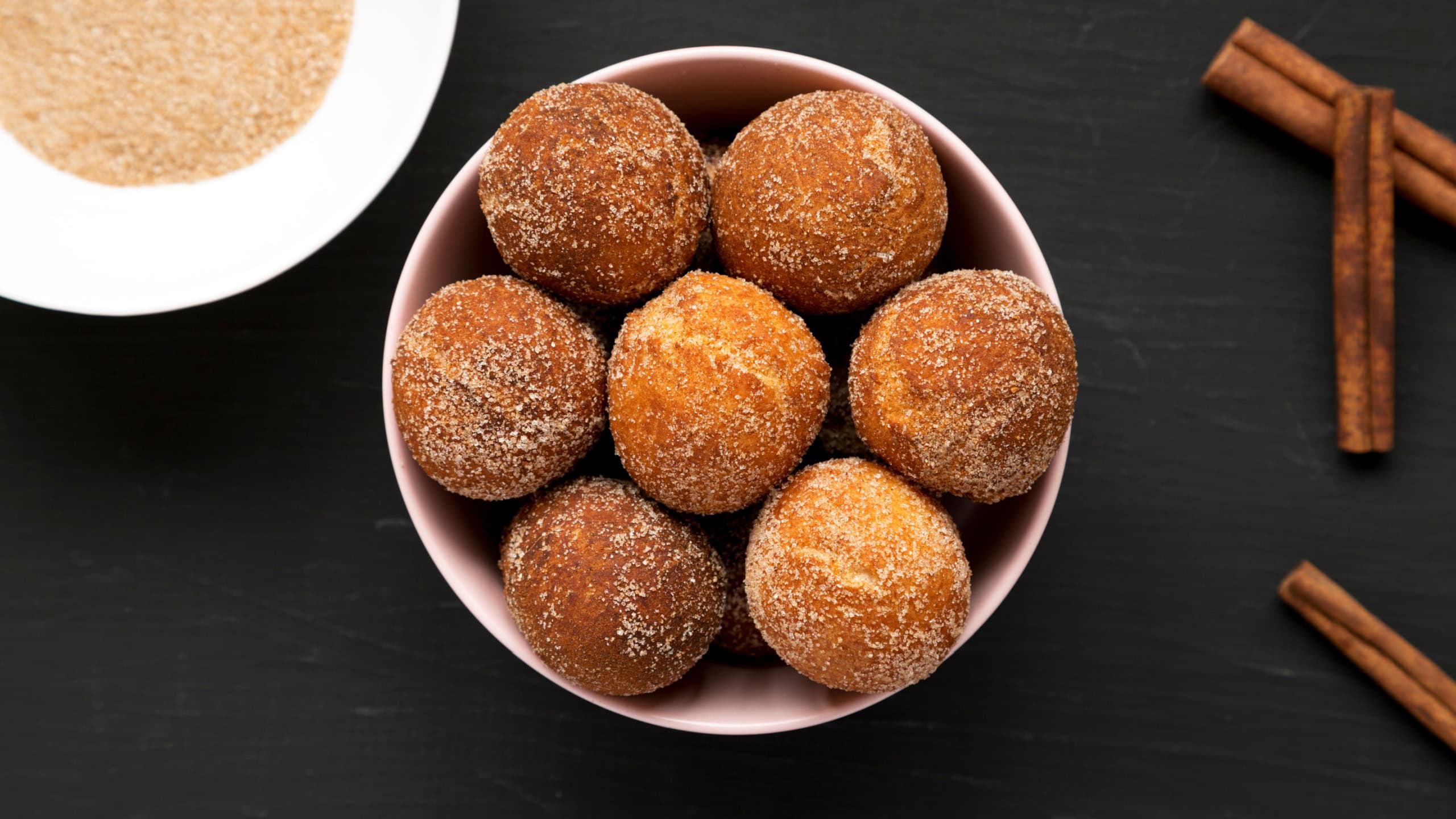 Homemade Fried Donut Holes in a pink bowl on a black surface