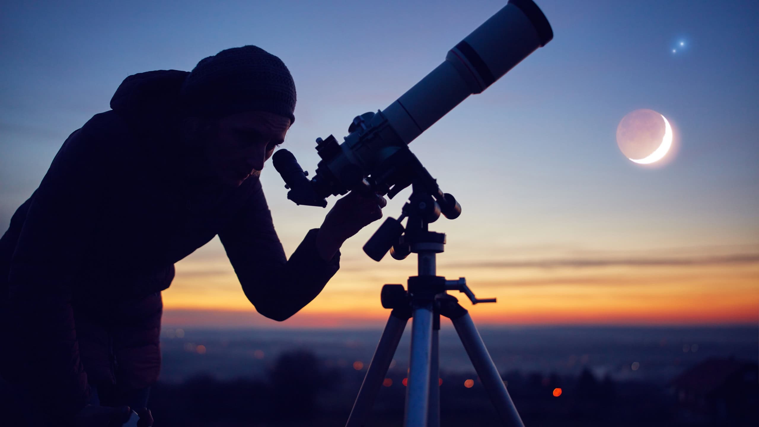 Woman looking at night sky with amateur astronomical telescope.