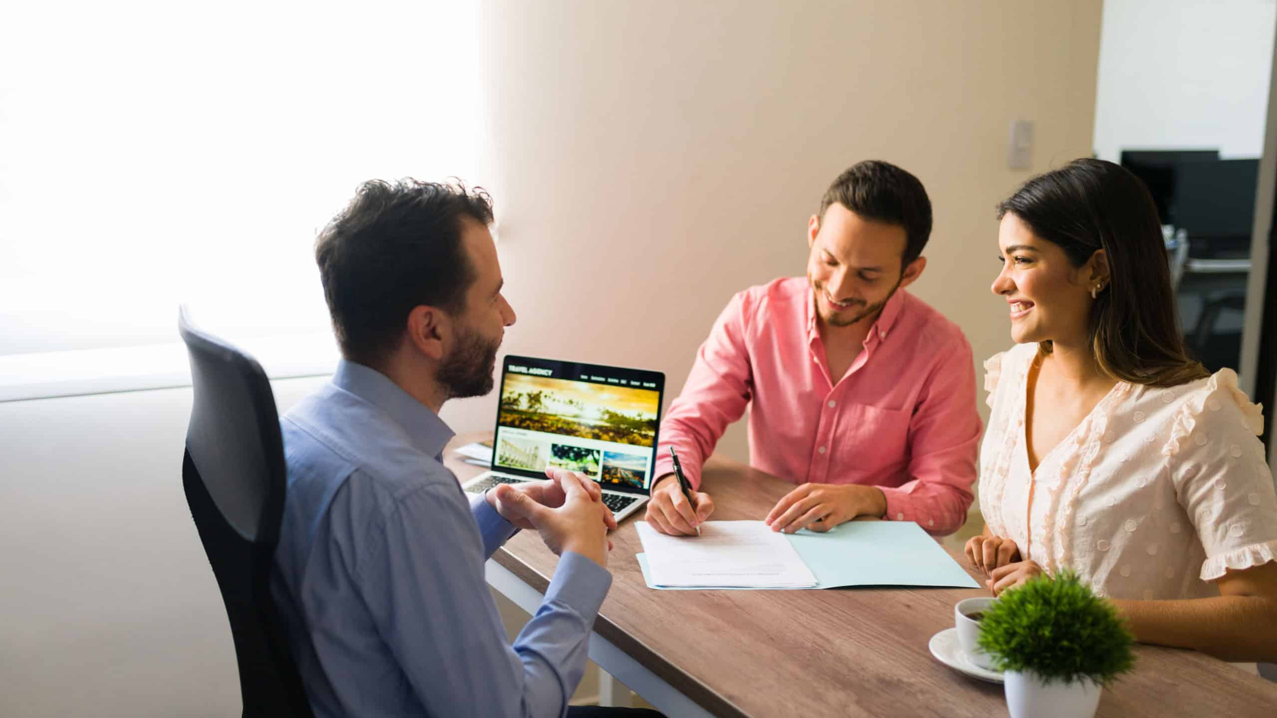 Excited couple signing a sales contract and timeshare at a travel agency and feeling happy for their upcoming holiday vacations