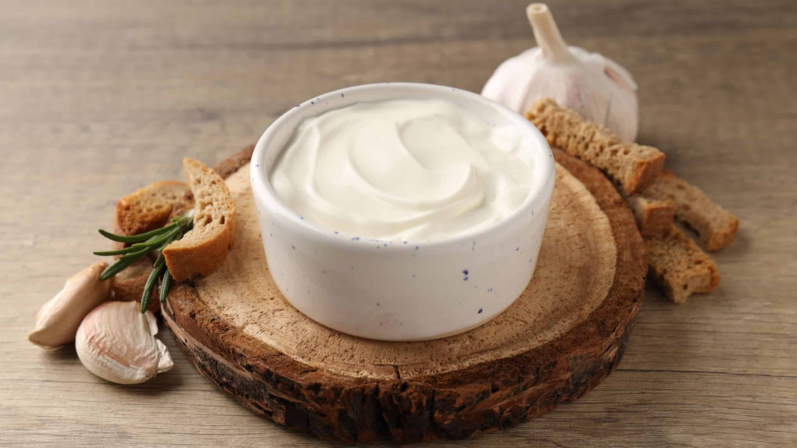 Garlic sauce, ingredients and snack on wooden background