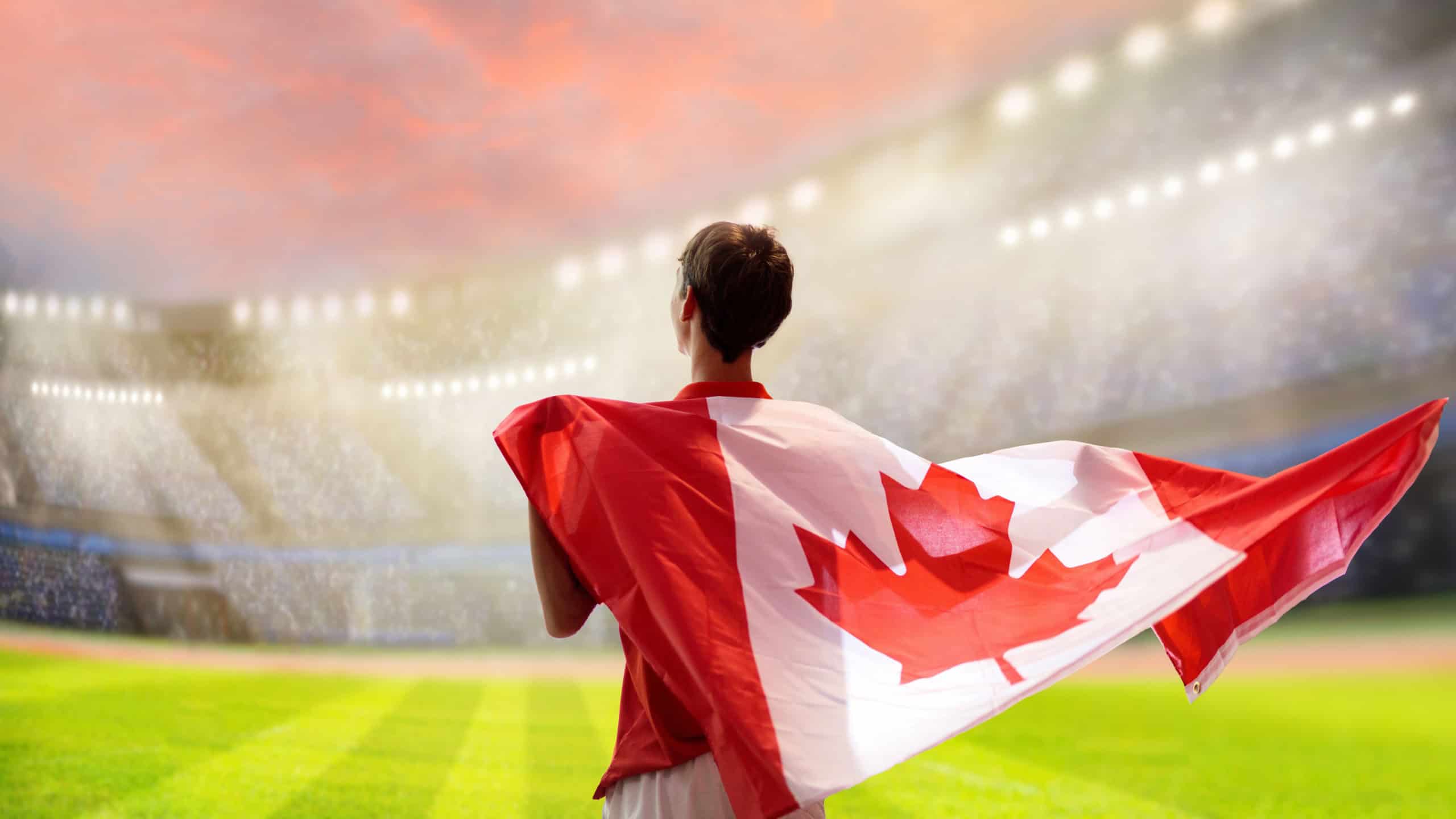 Canada football supporter on stadium. Canadian fans on soccer pitch watching team play. Group of supporters with flag and national jersey cheering for Canada. Championship game.